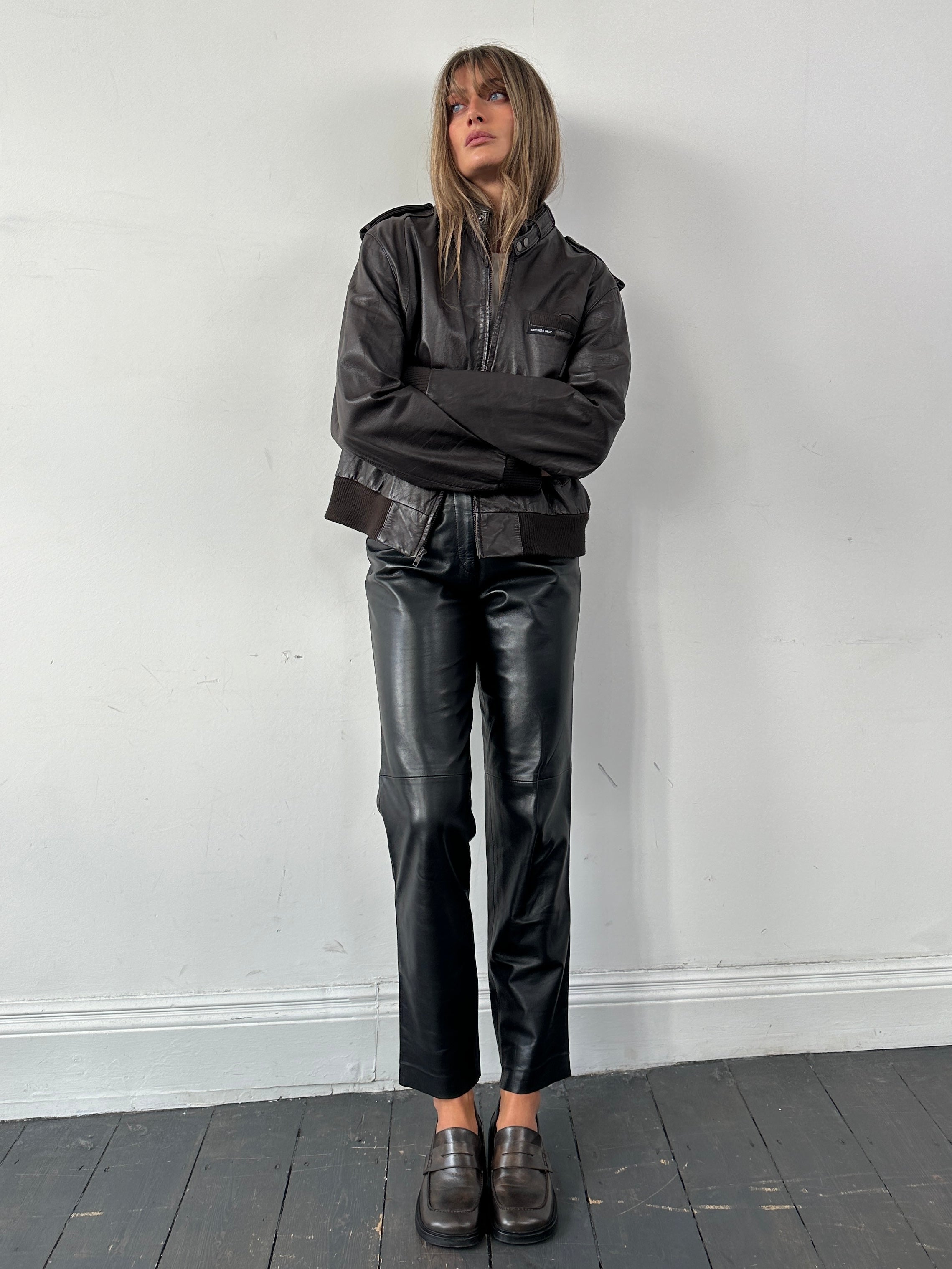 Vintage high waisted smooth leather trousers in black, showing front view with tailored fit and sleek design.