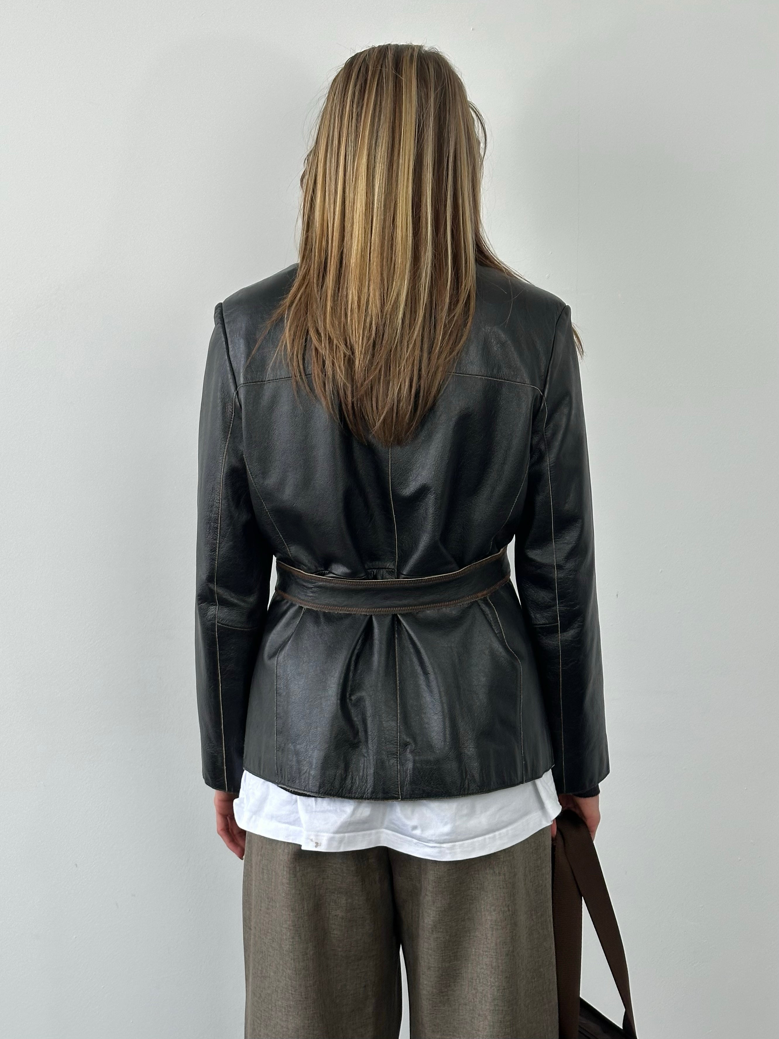 Vintage 1990s leather jacket with belt, black leather, classic fit, front zipper, and collar detail, displayed on a hanger.