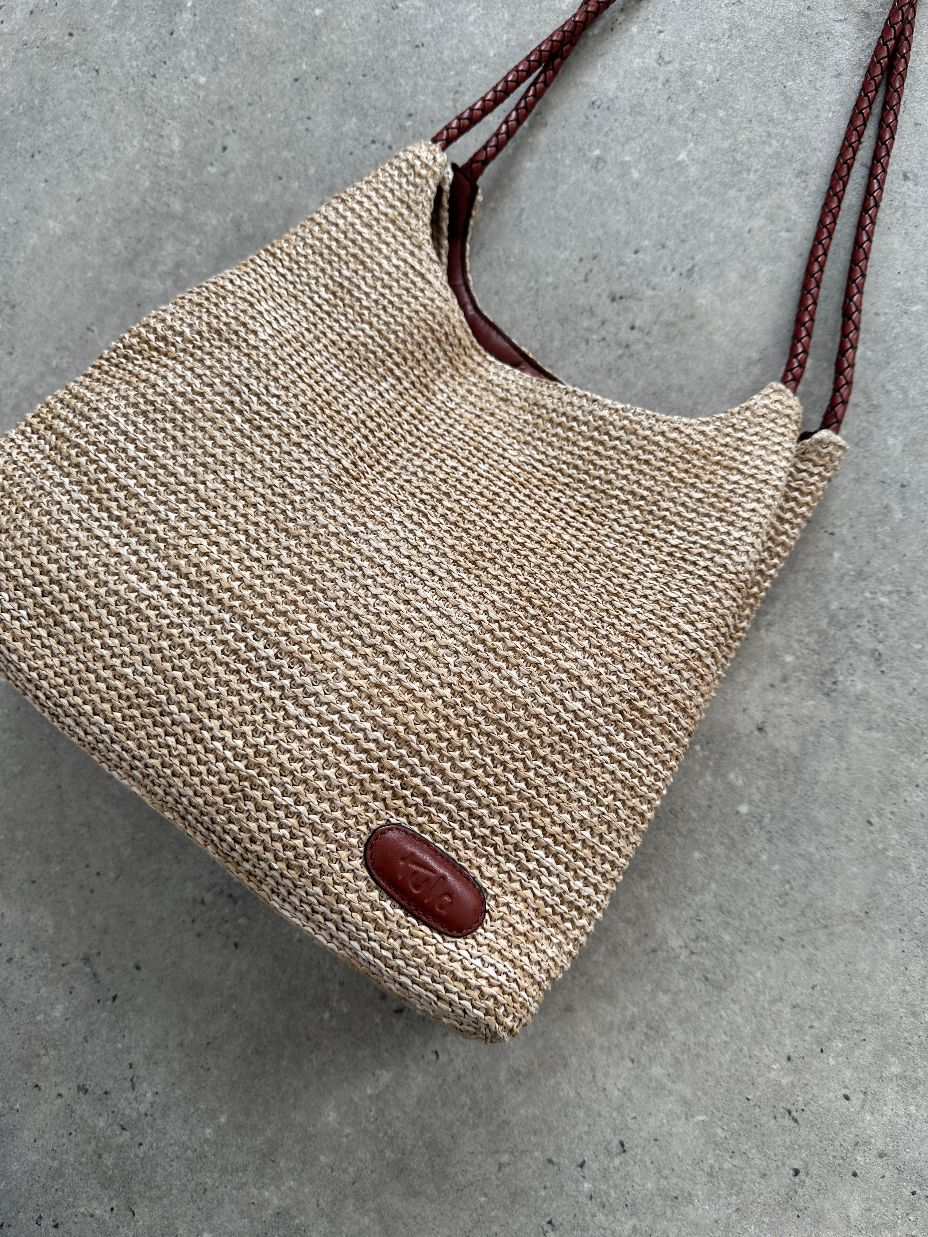 Vintage leather and straw shoulder bag with adjustable strap, featuring a classic, rustic design and handcrafted details.