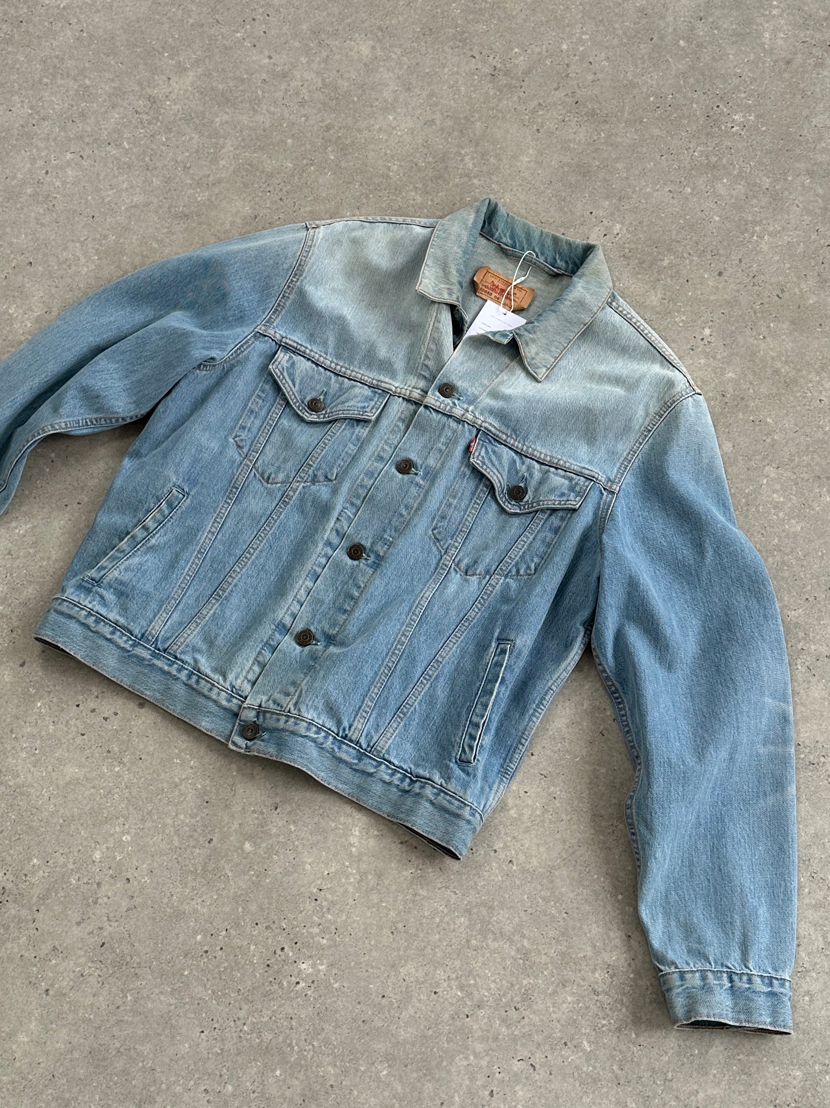 Levi’s faded denim jacket in size large, shown on a hanger with a classic button-up design and distressed denim texture.
