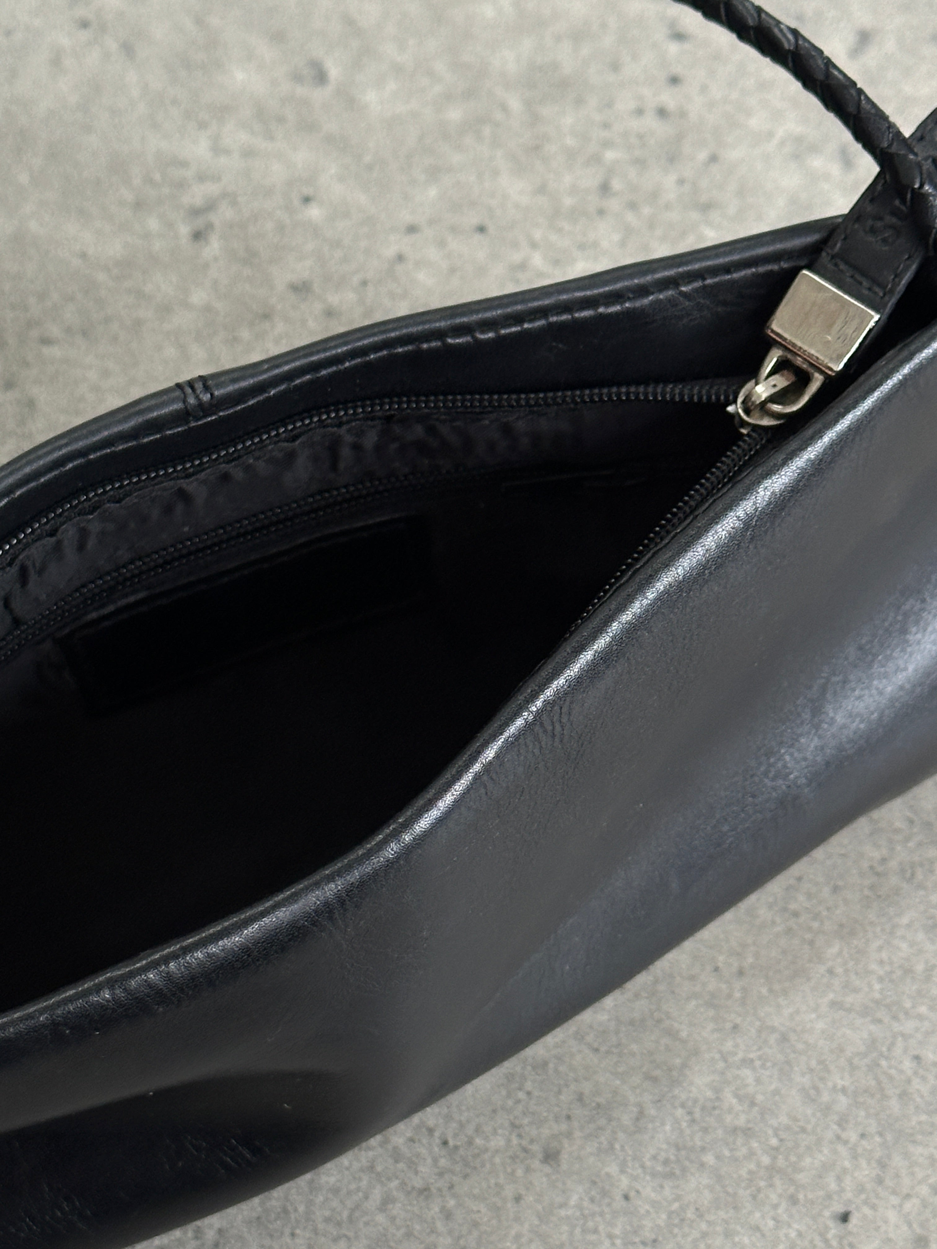 Vintage leather shoulder bag with adjustable strap, classic design, and textured brown leather exterior.