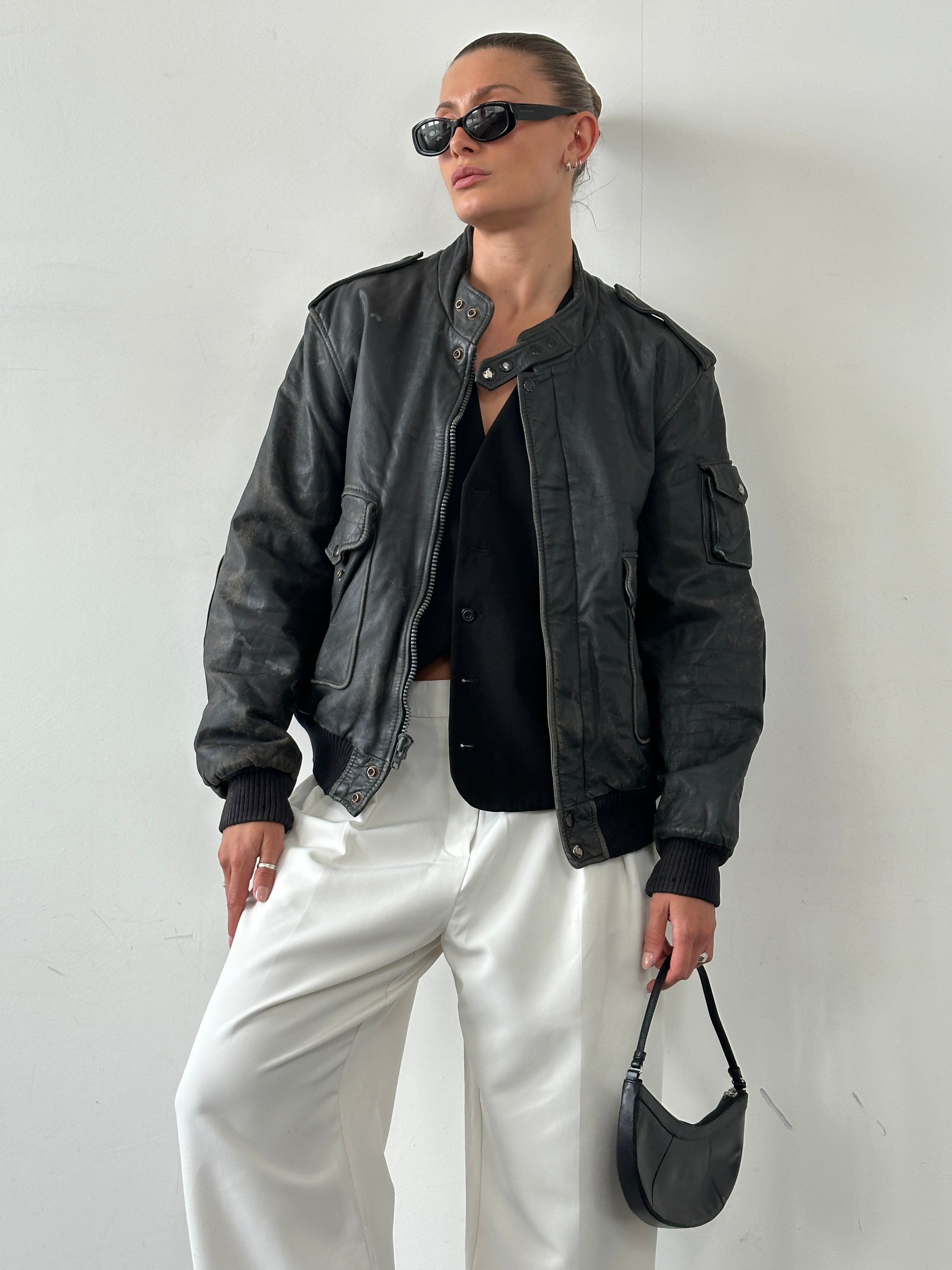 Vintage distressed leather bomber jacket in M/L size, showcasing rugged texture and classic style with a worn-in look.