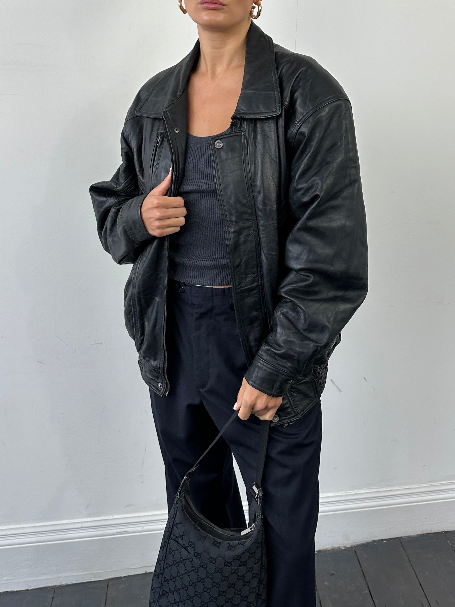 Vintage leather bomber jacket in XL style, featuring classic design and detailed stitching, displayed on a hanger.