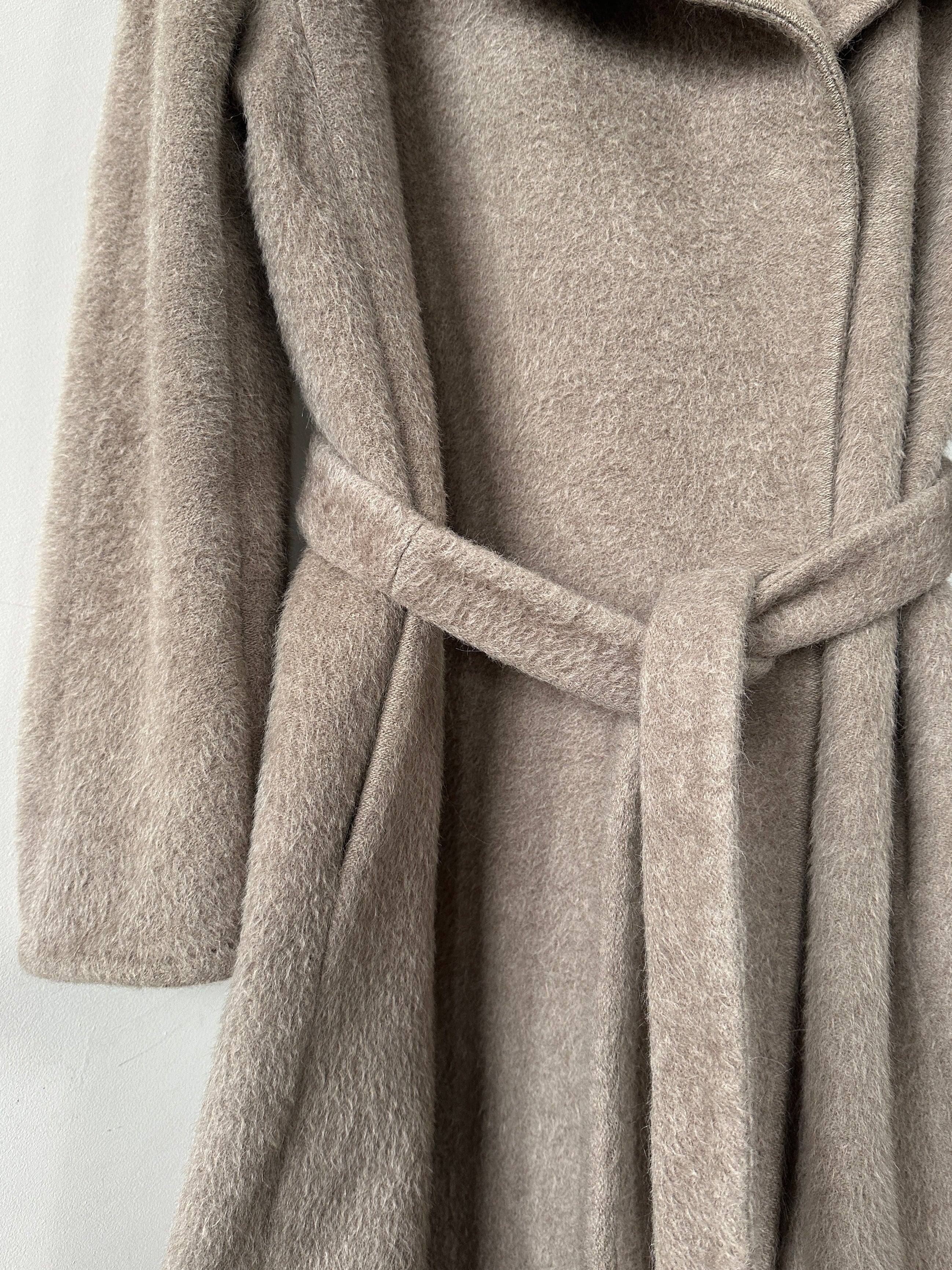 Max Mara alpaca wool belted wrap coat in neutral color, displayed hanging on a wooden hanger.