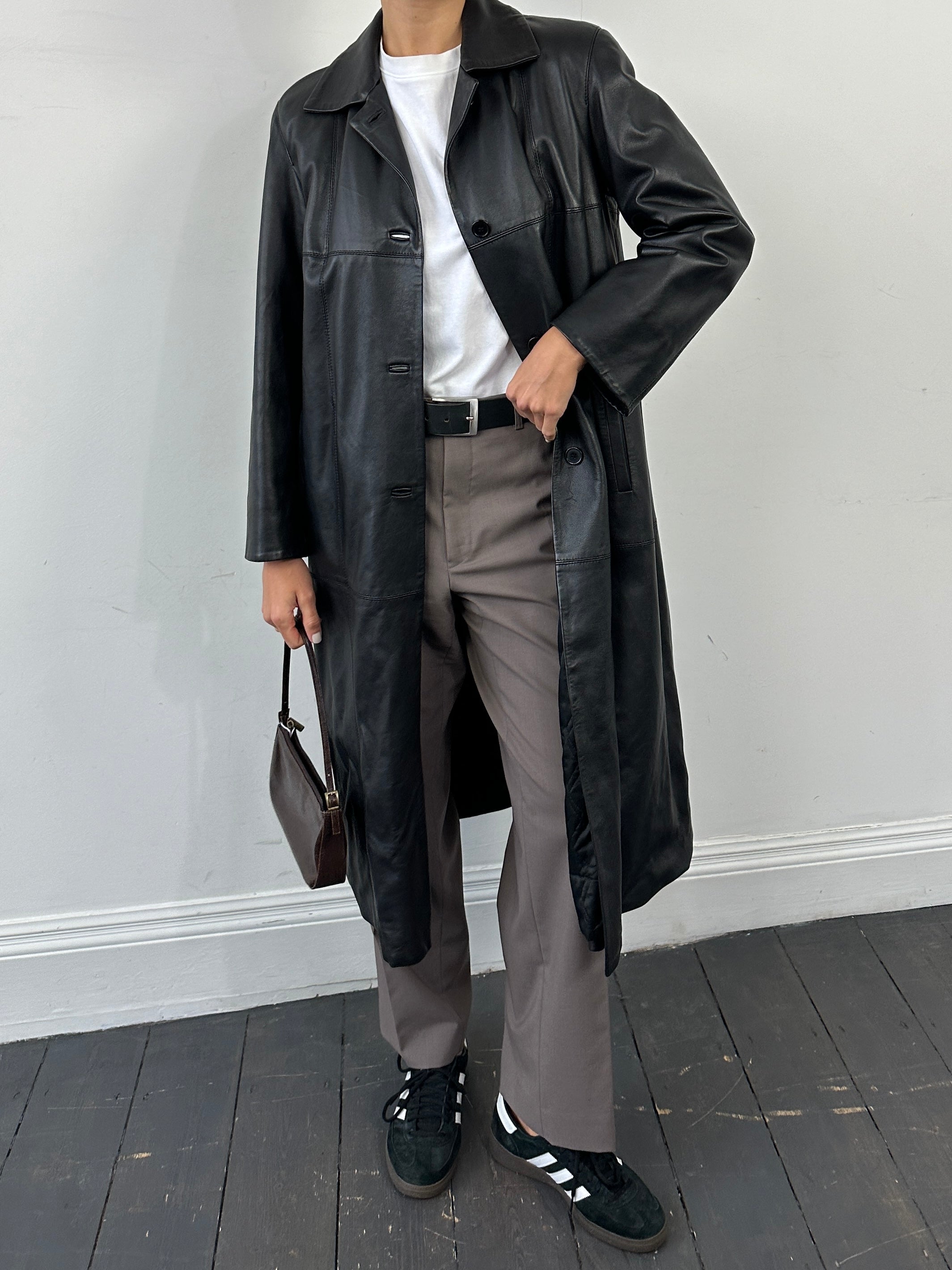 Conbipel smooth leather trench coat in size L hanging on a rack, showcasing its sleek, tailored design and classic style.