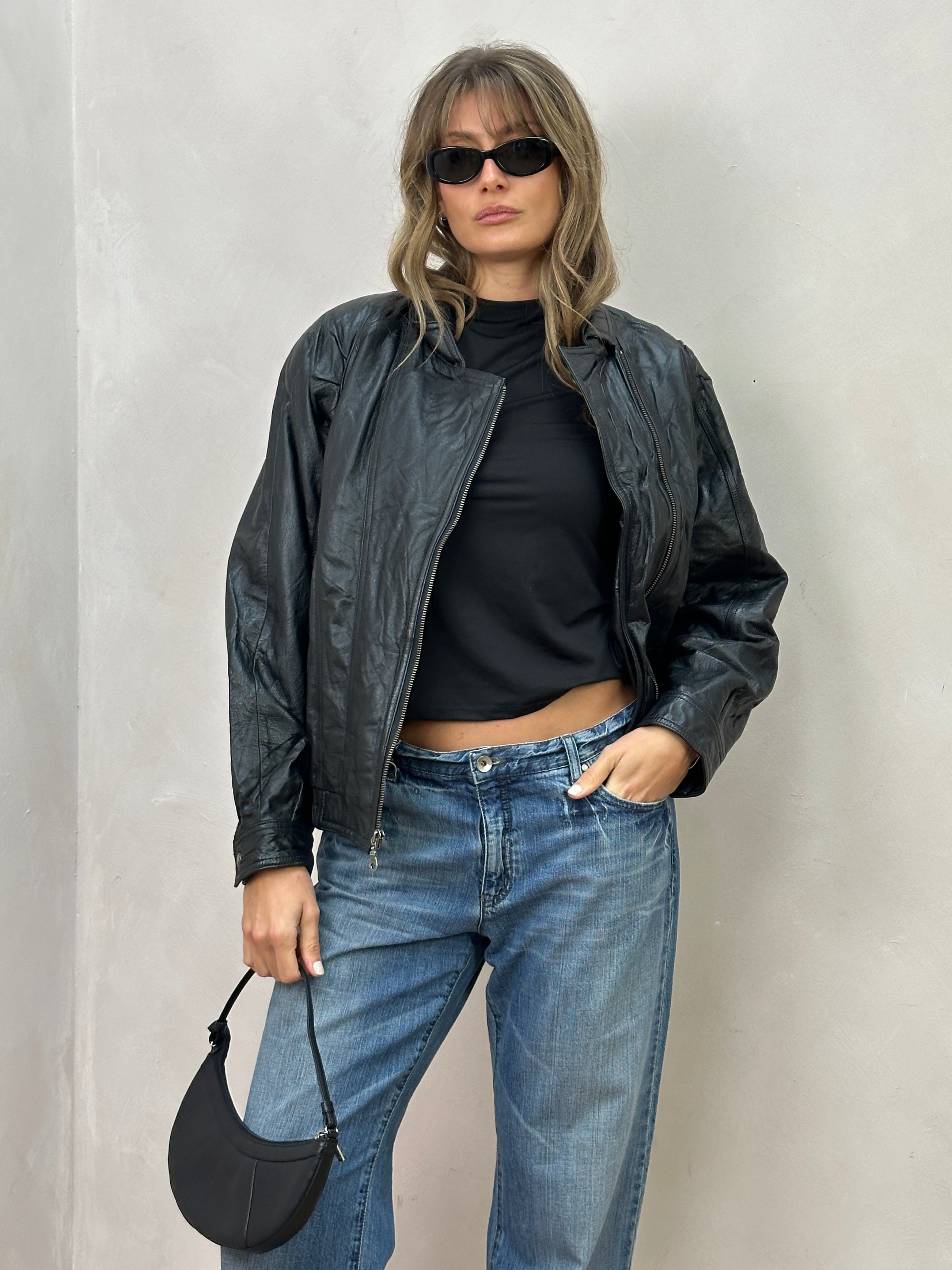 Vintage leather biker jacket in size S/M, featuring classic design and rugged style, displayed on a hanger against a neutral background.