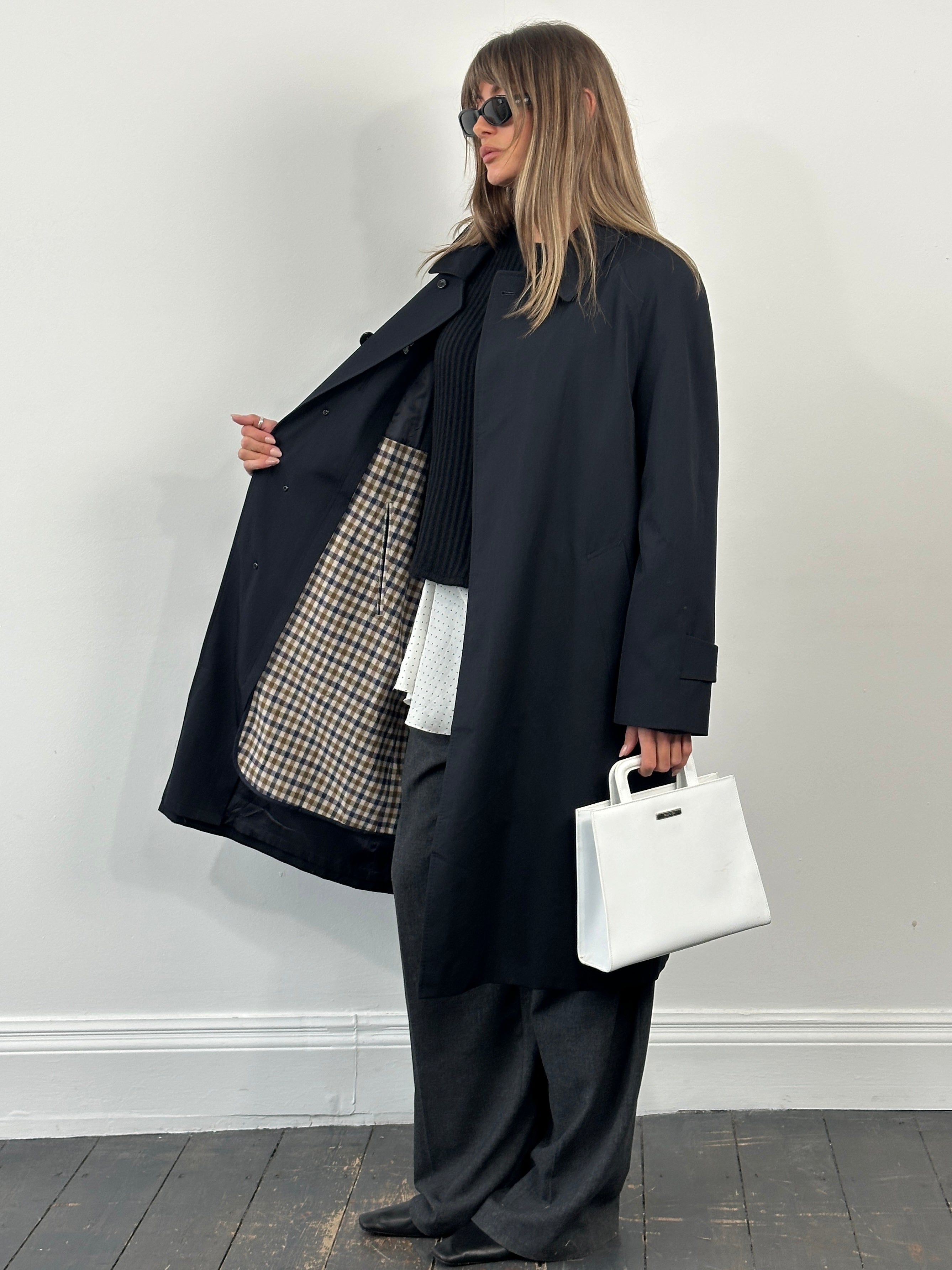 Aquascutum 1990s cotton trench coat in size L, beige with classic double-breasted design and belt, displayed on a hanger.