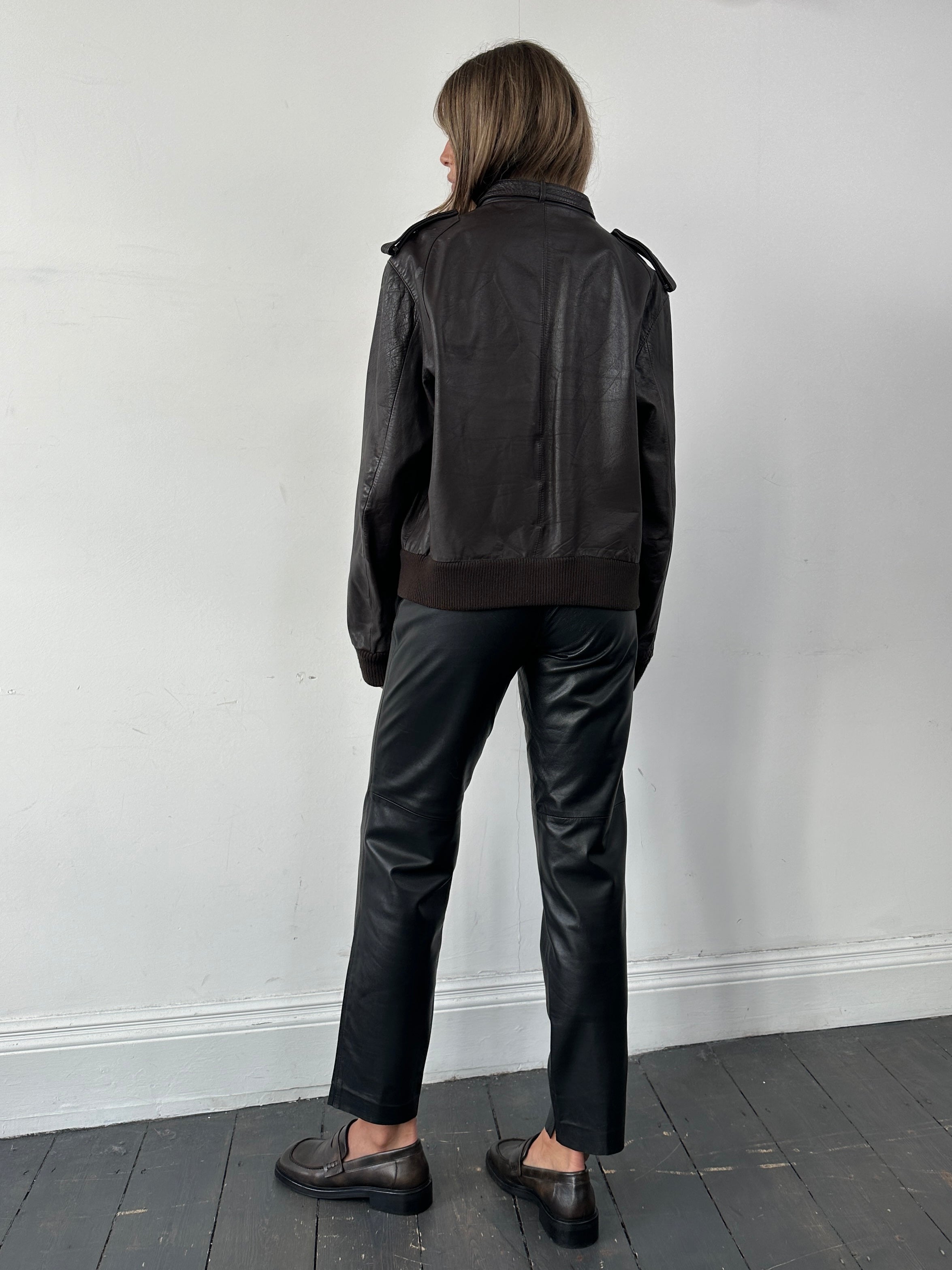 Vintage high-waisted smooth leather trousers in size W26, showcasing the sleek fit and classic design from the front view.