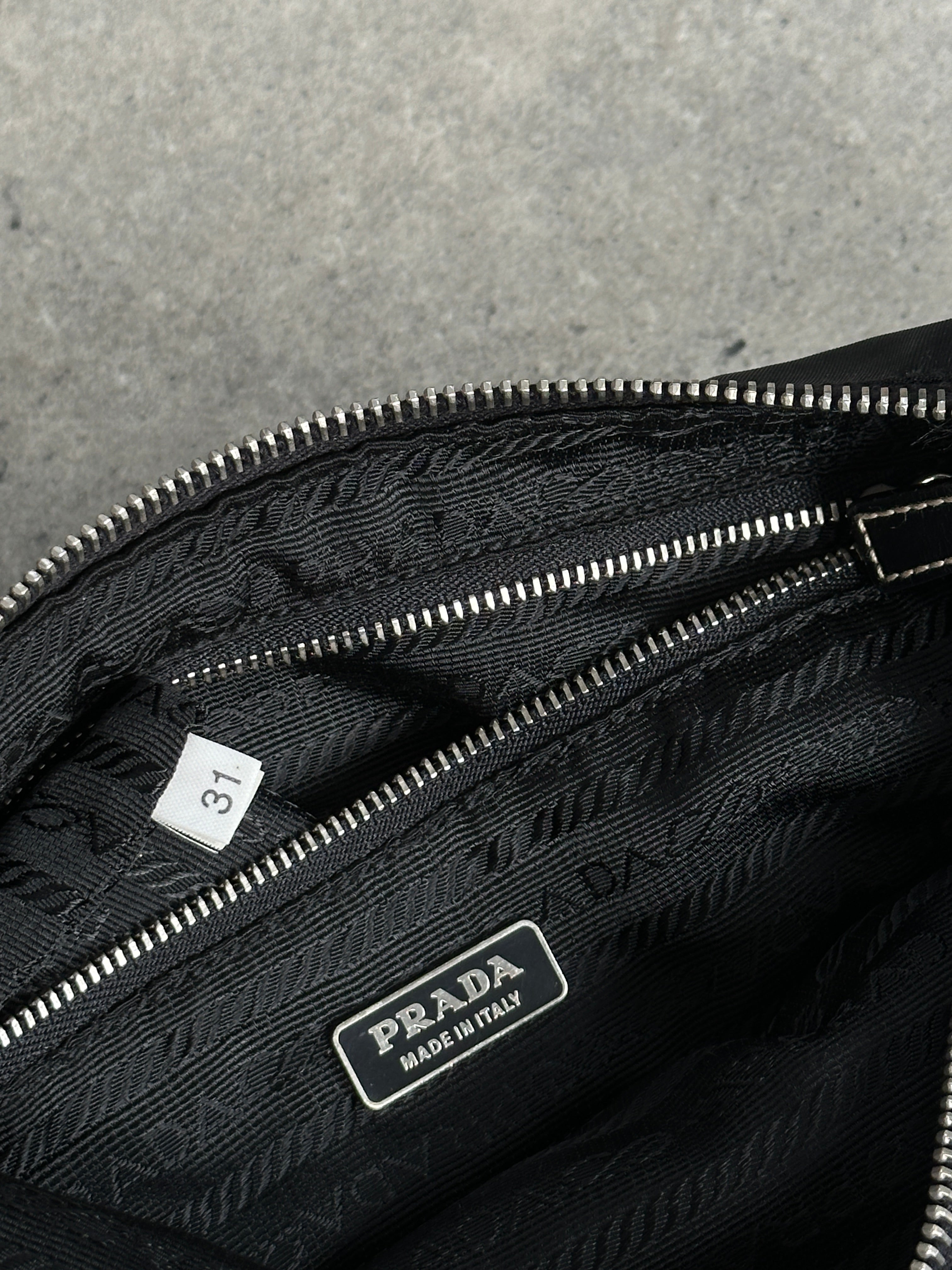 Prada nylon shoulder bag with chrome logo hardware and adjustable strap, featuring a sleek, modern design.