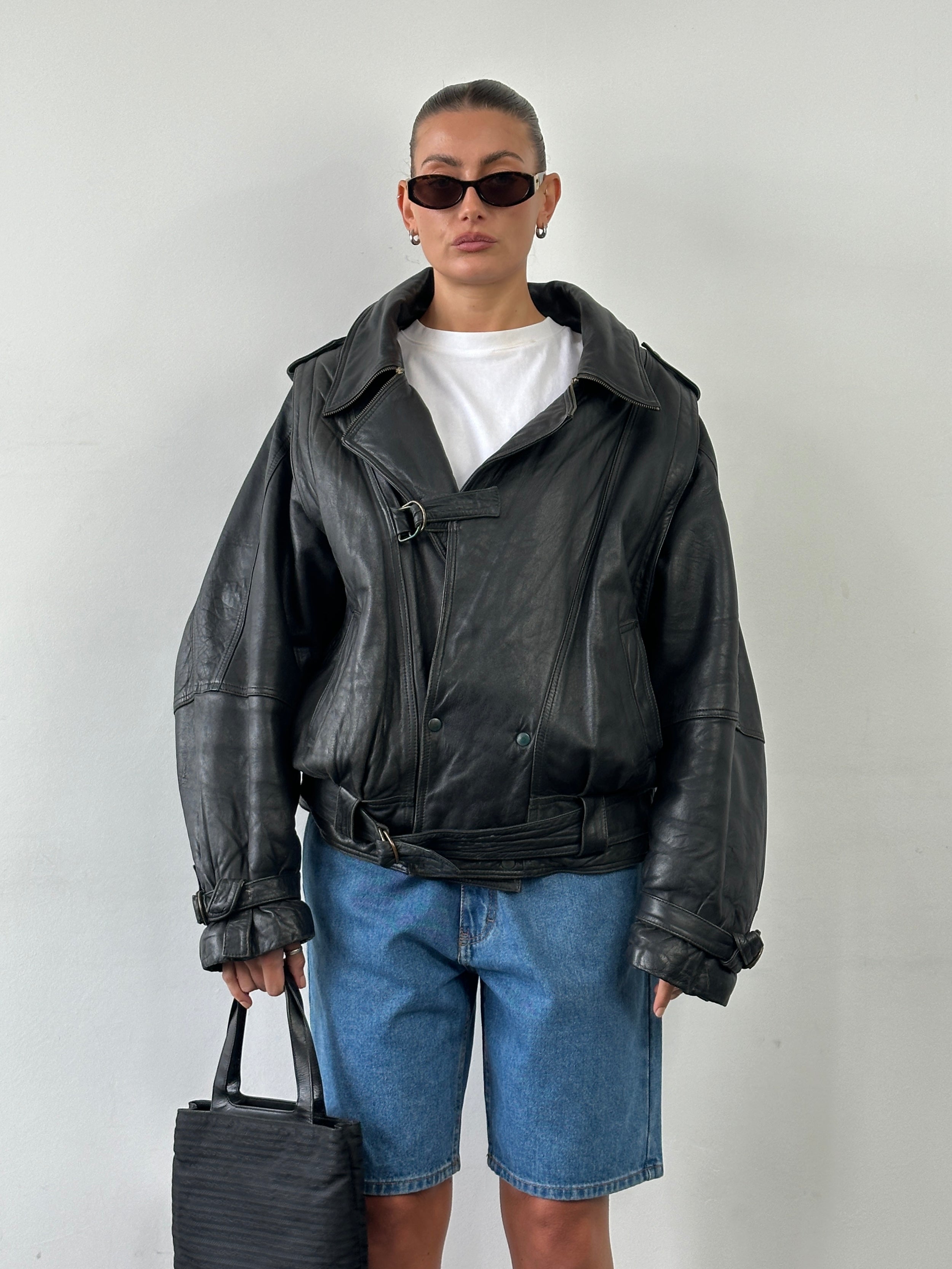 Vintage leather jacket with a belted buckle, in size XL, featuring a classic design and visible stitching.
