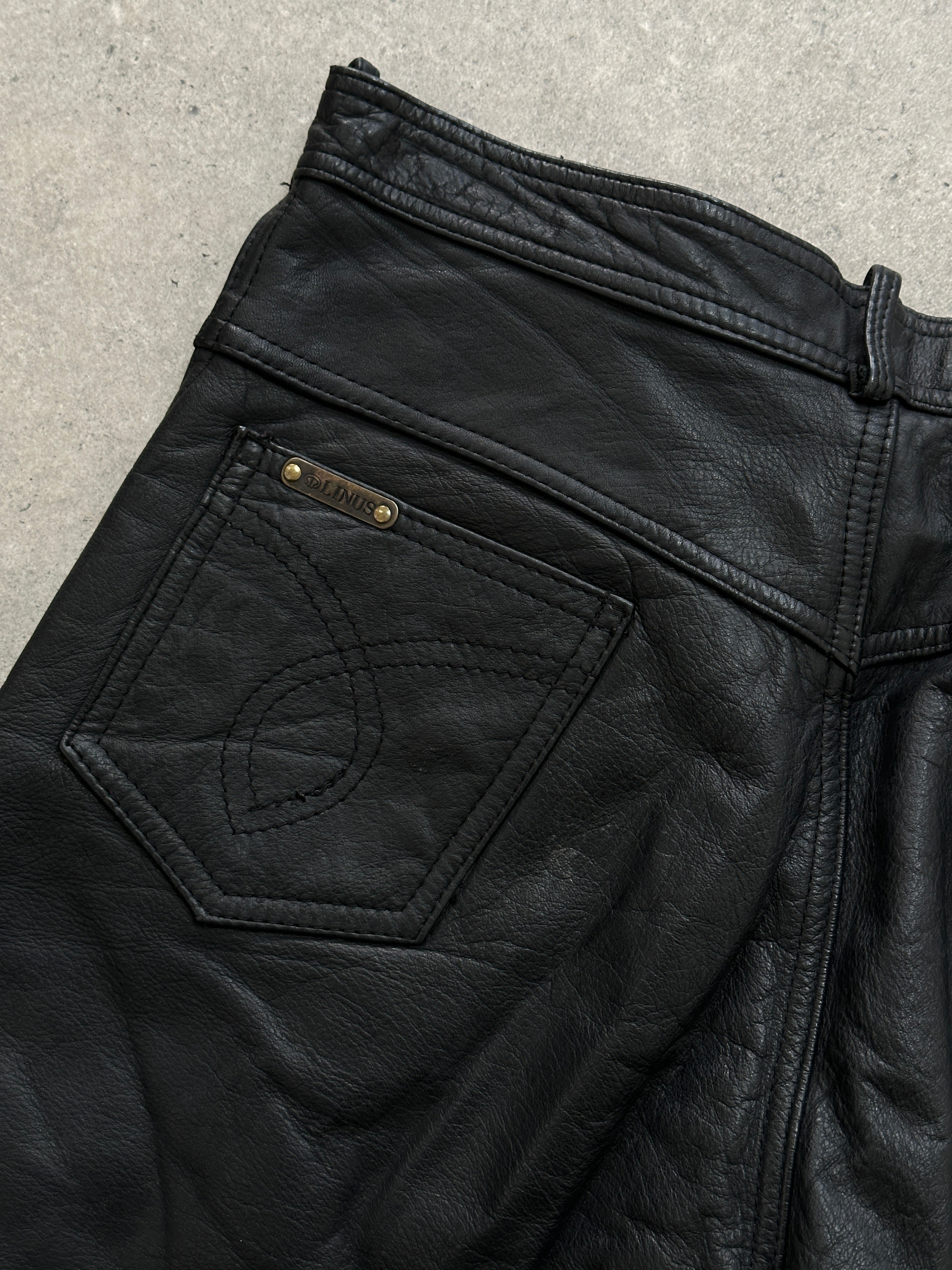 Vintage high waisted straight leg leather trousers in size W28, showing classic black leather with a sleek fit and vintage style.