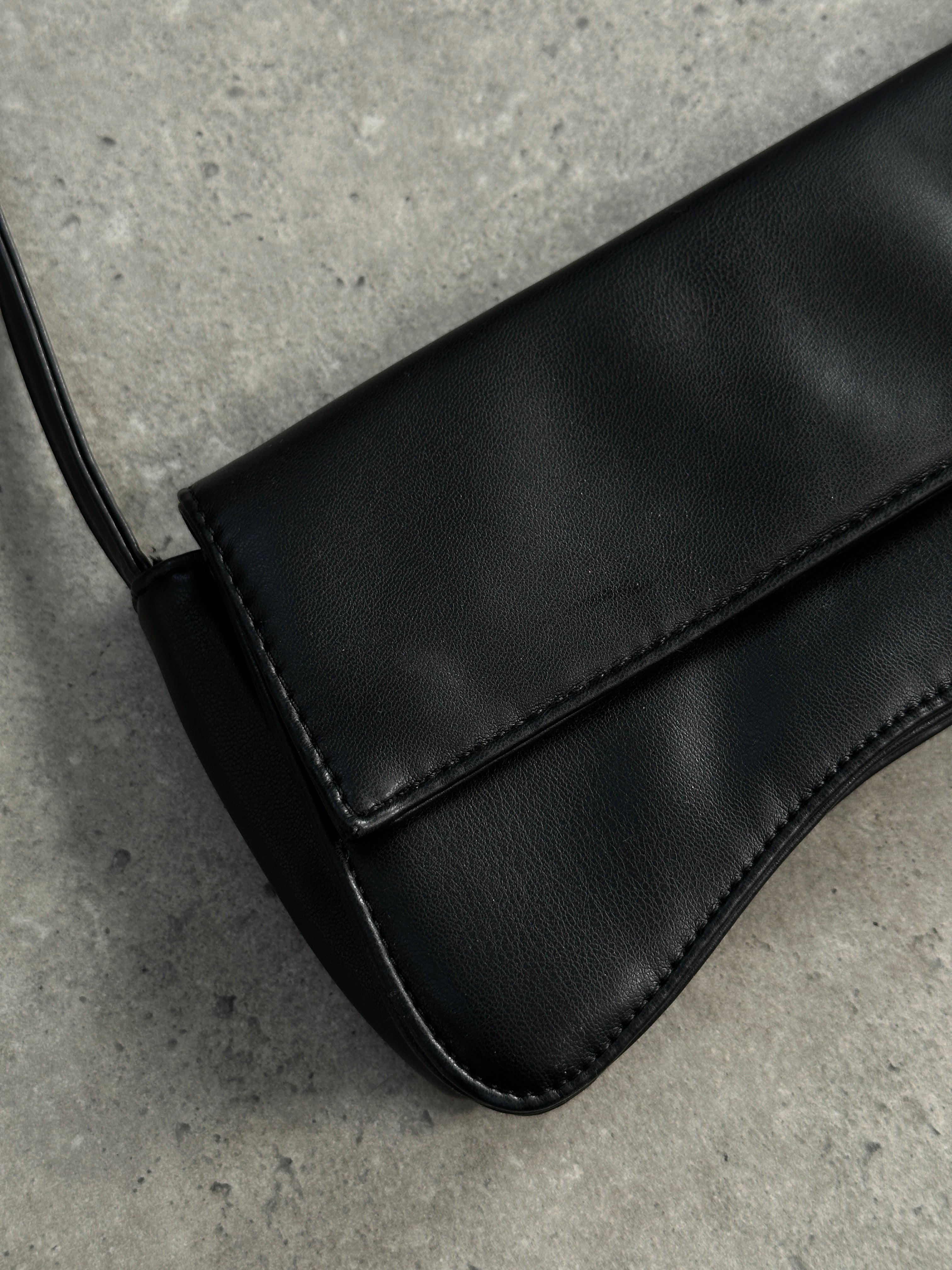 Vintage faux leather curved shoulder bag with adjustable strap and vintage-inspired design, displayed on a neutral background.