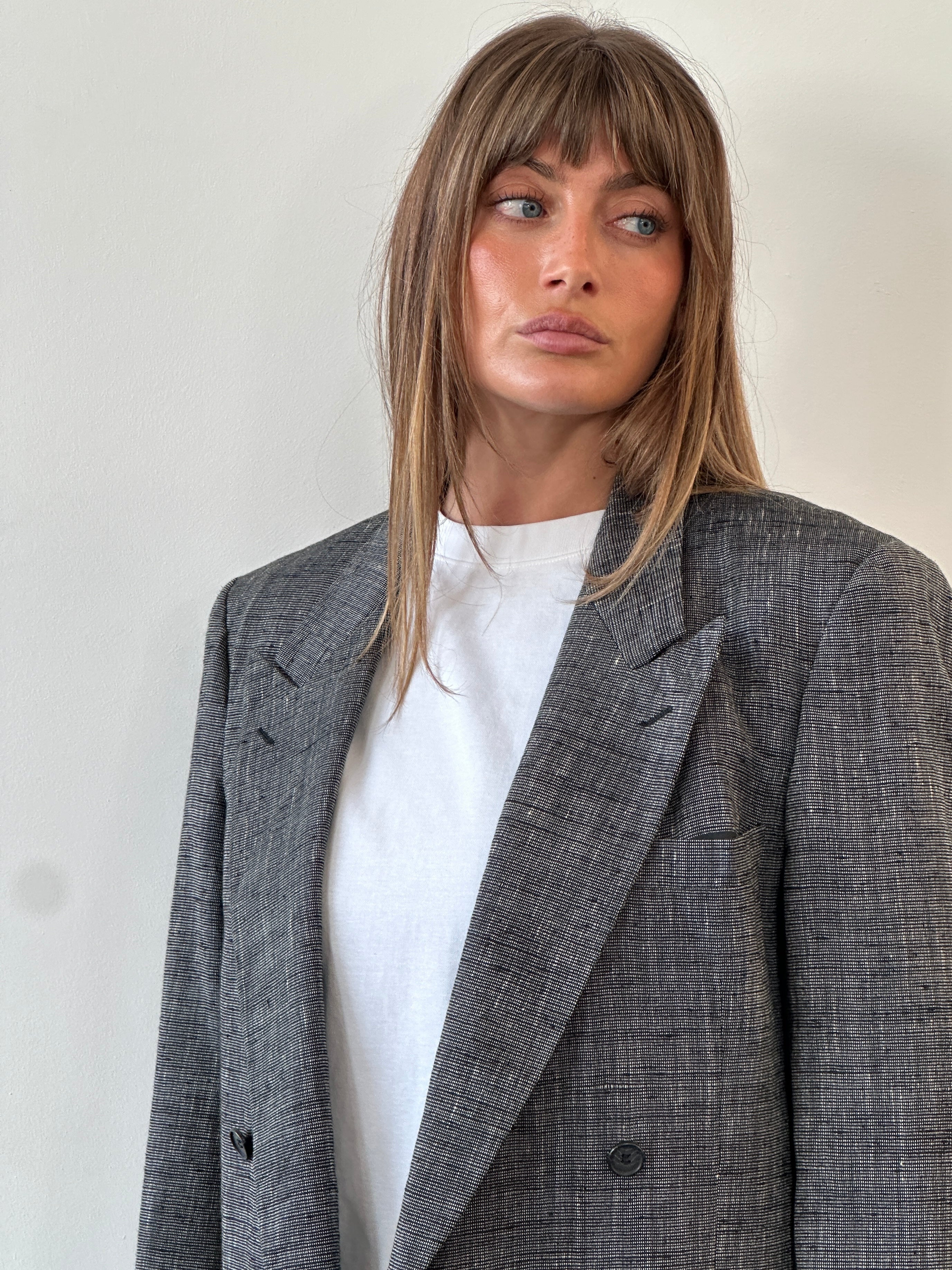 Yves Saint Laurent men's double-breasted blazer in 1980s style, tailored fit, dark fabric, featuring peaked lapels and structured shoulders.
