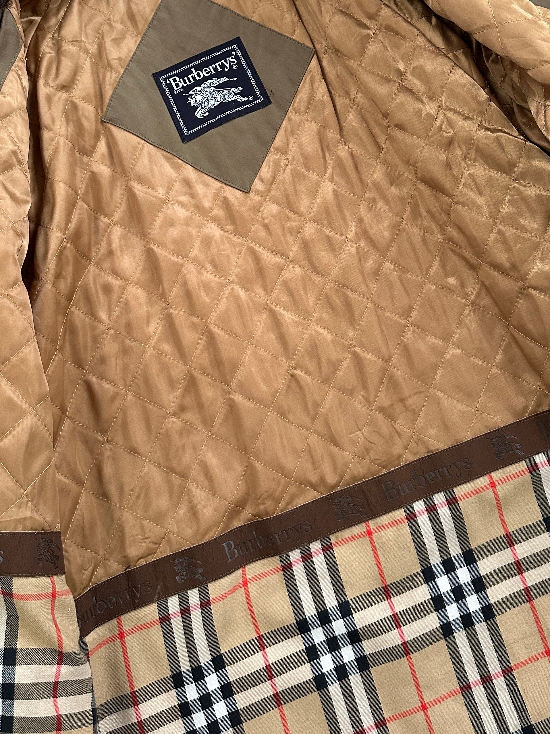 Burberry 1990s cotton field trench coat in XL/XXL, beige color, classic design with belt and double-breasted buttons, displayed on a hanger.