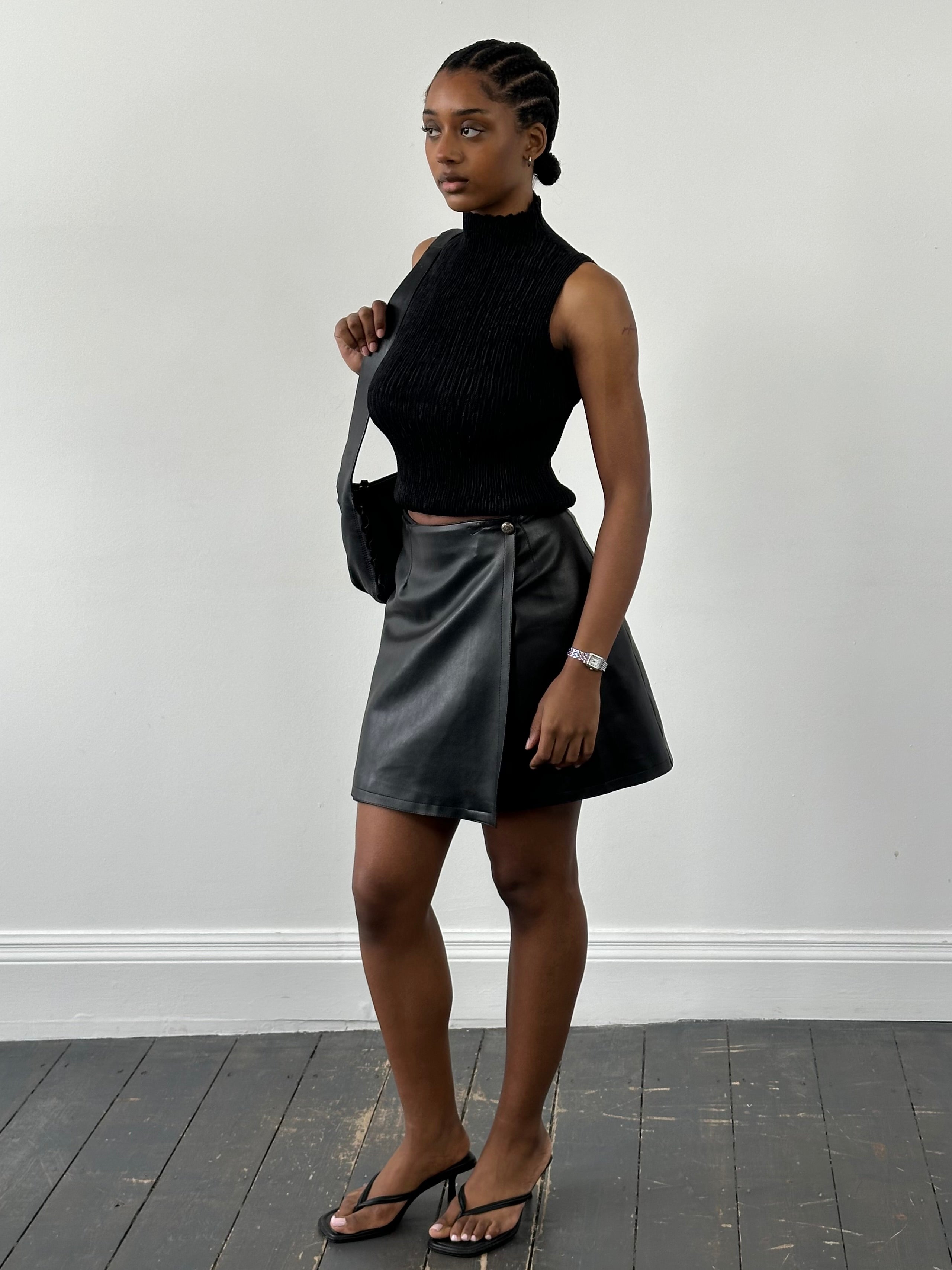 Vintage faux leather wrap mini skirt in black, showcasing its stylish design and fitted silhouette.