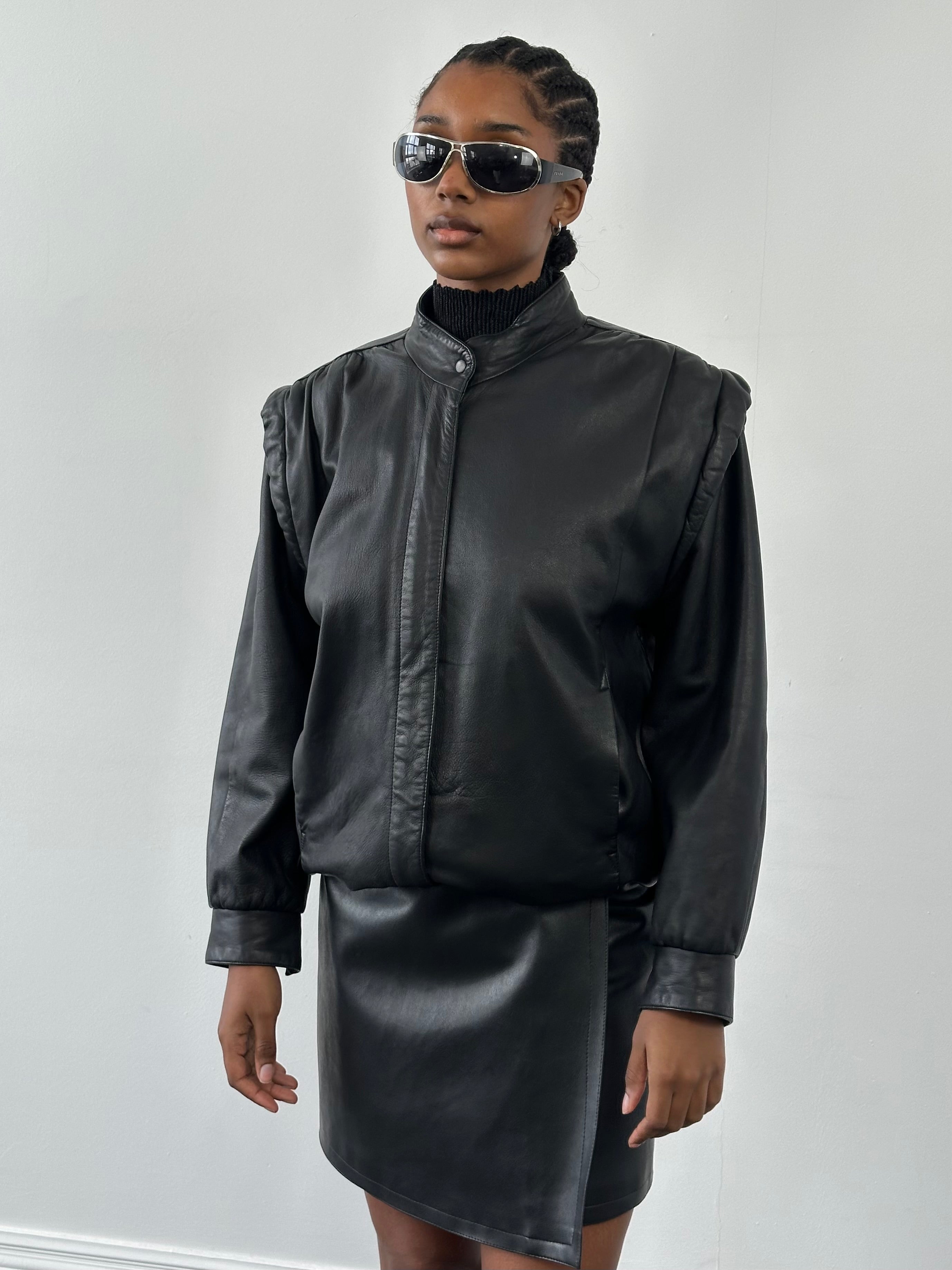 Vintage 1990s leather bomber jacket, size medium, with classic design and worn leather texture, displayed on a hanger.