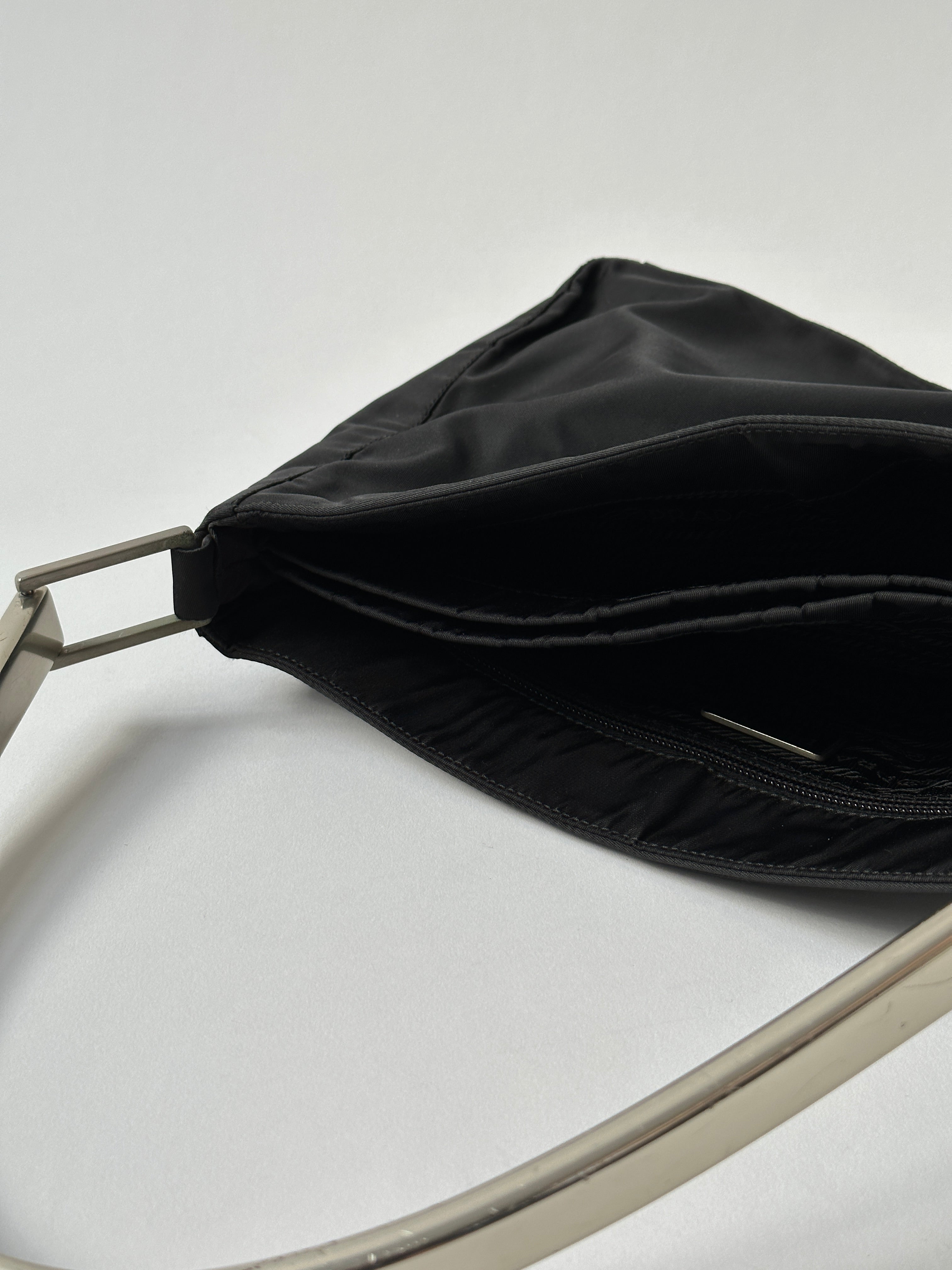 Prada nylon shoulder bag with metal handle, featuring a sleek design and durable fabric, perfect for stylish everyday use.