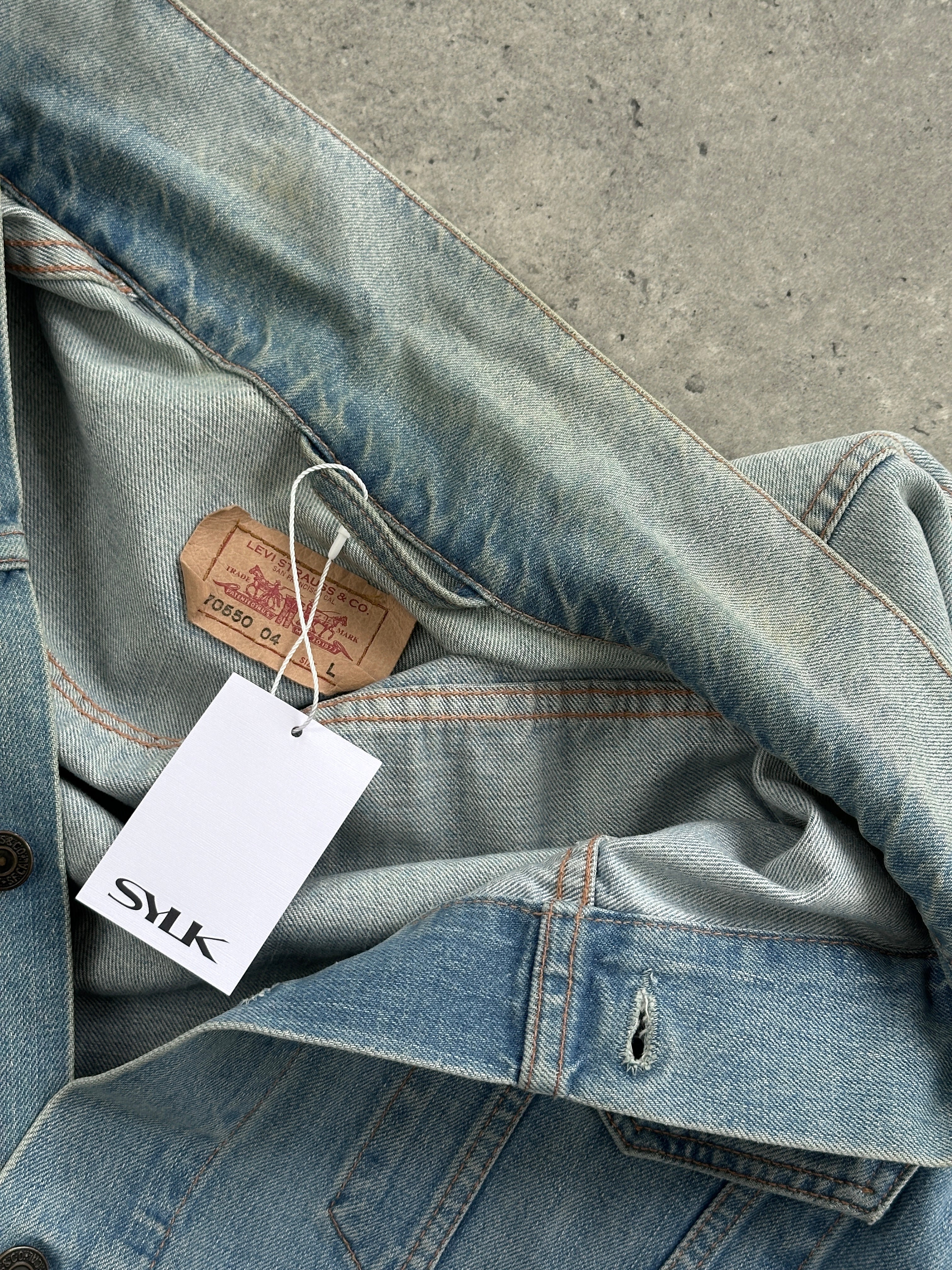 Levi’s faded denim jacket in size L displayed on a hanger, showcasing classic blue denim with a slightly distressed finish.