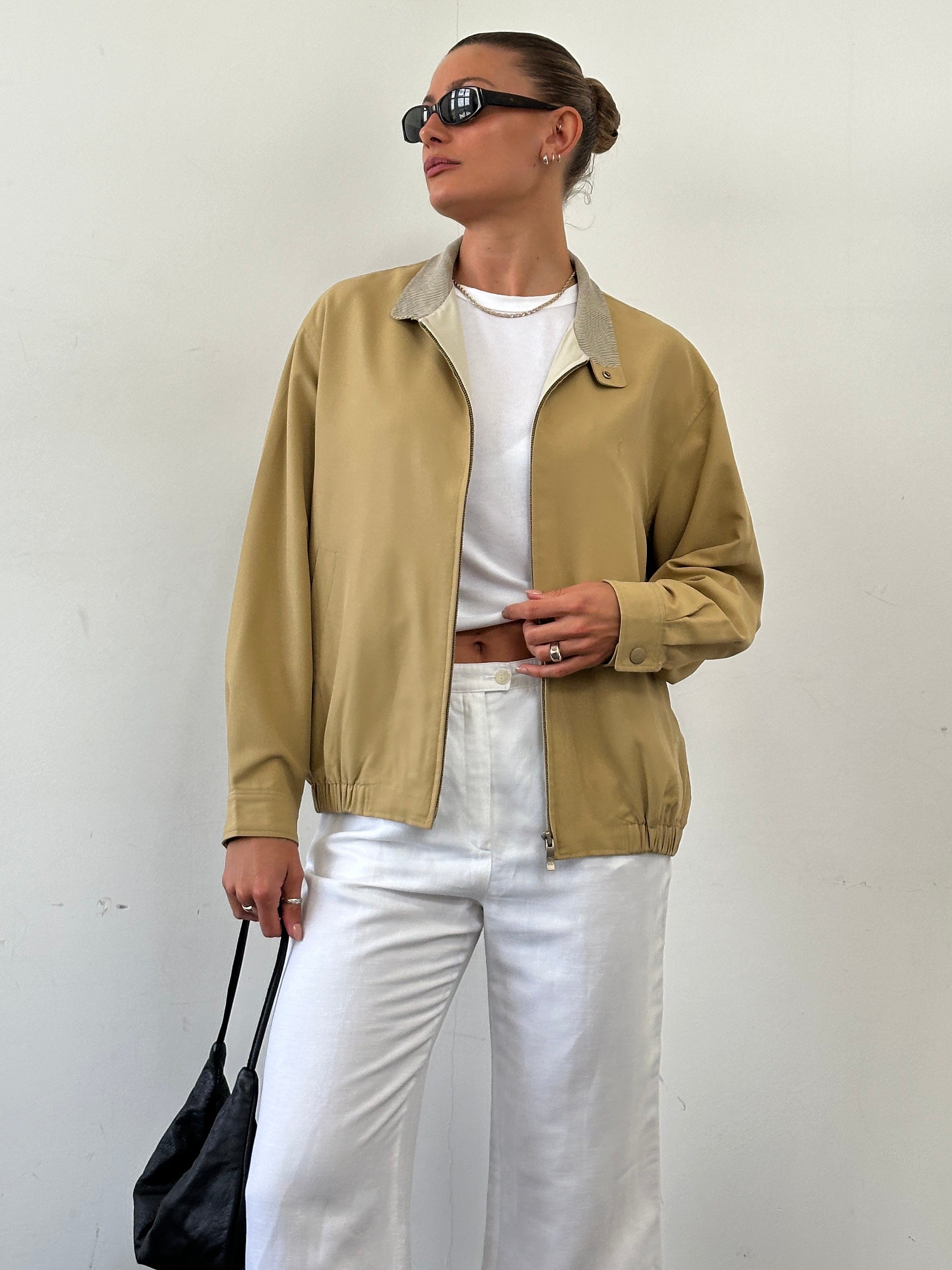 Yves Saint Laurent logo bomber jacket in black, displayed on a hanger, showcasing its sleek design and signature branding.