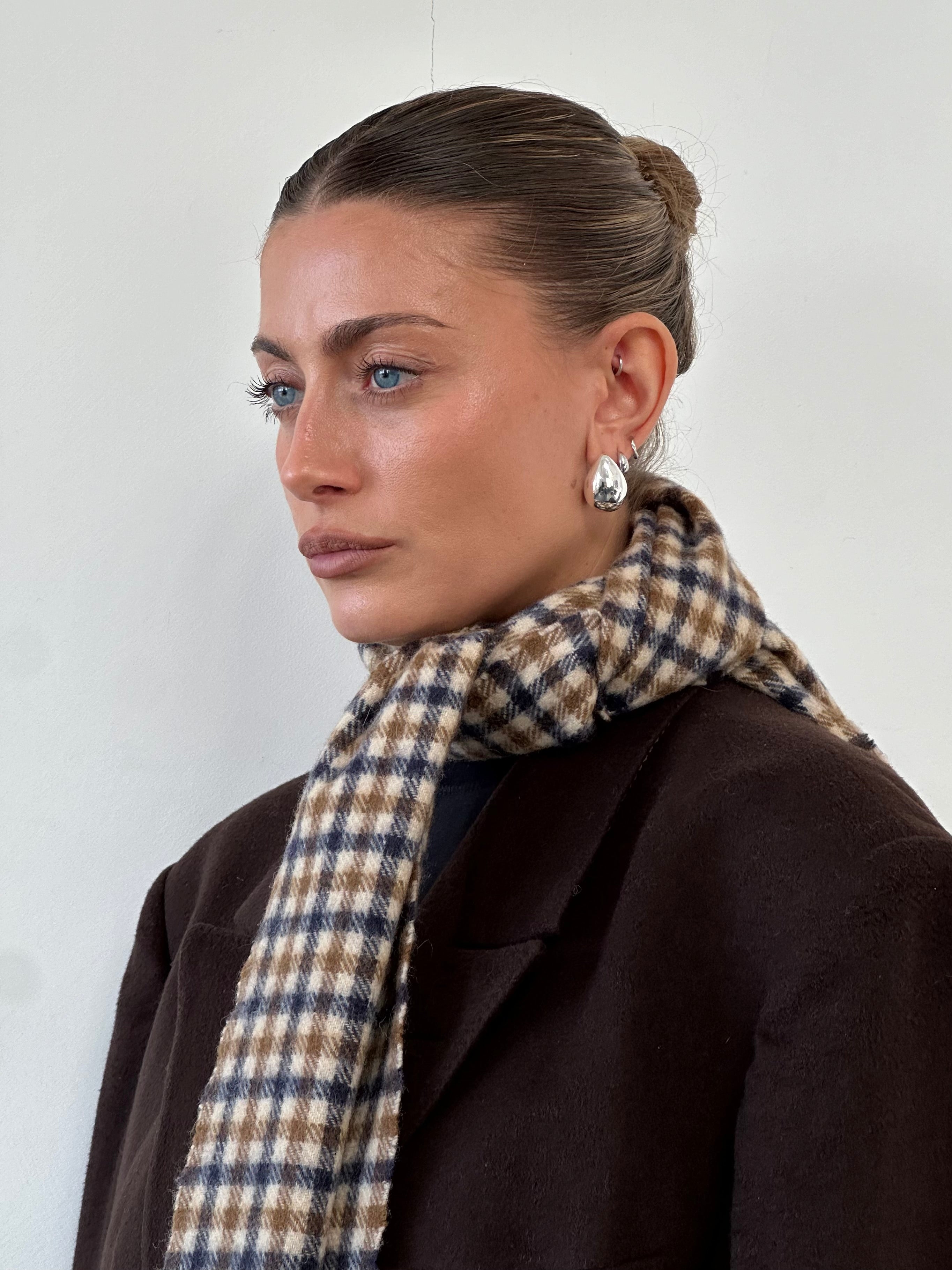Aquascutum cashmere wool check scarf draped over a surface, showcasing its soft texture and classic check pattern.