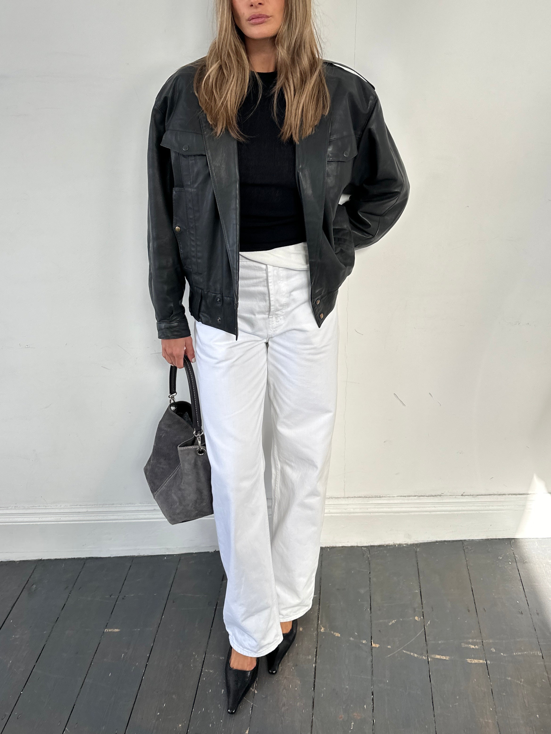 Vintage leather bomber jacket in size small, featuring classic design with ribbed cuffs and collar, worn by a person.