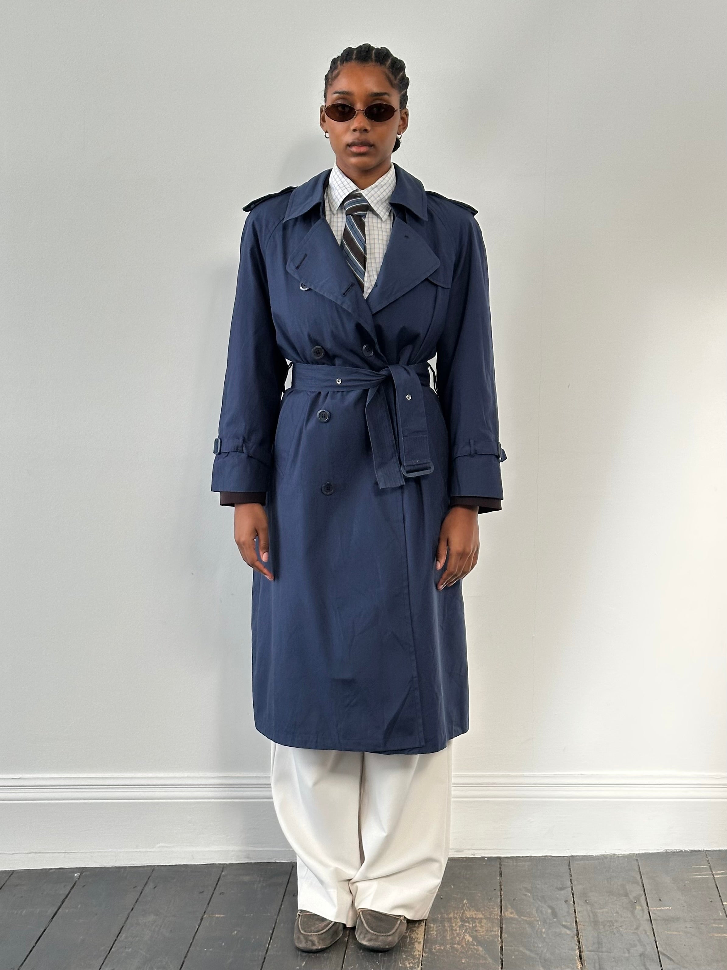 London Fog 1990s double-breasted cotton trench coat in classic beige, displayed on a hanger against a plain background.
