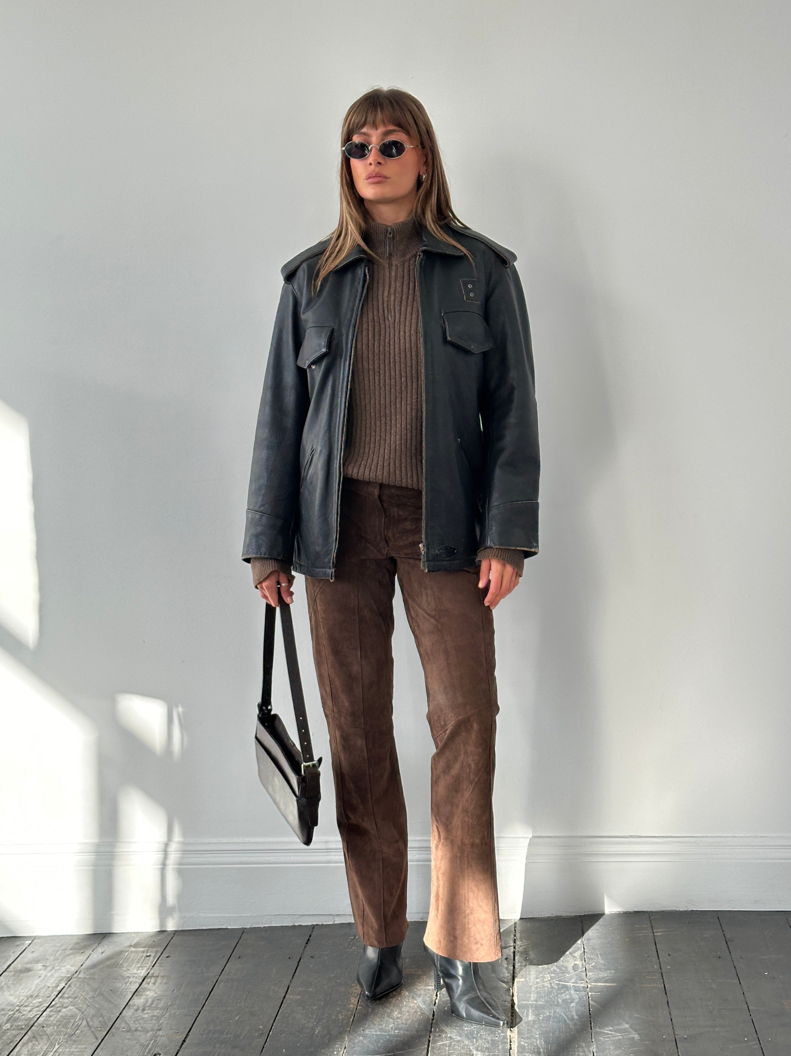Vintage 1990s aged leather jacket with distressed finish, classic style, and rugged texture, displayed on a hanger.