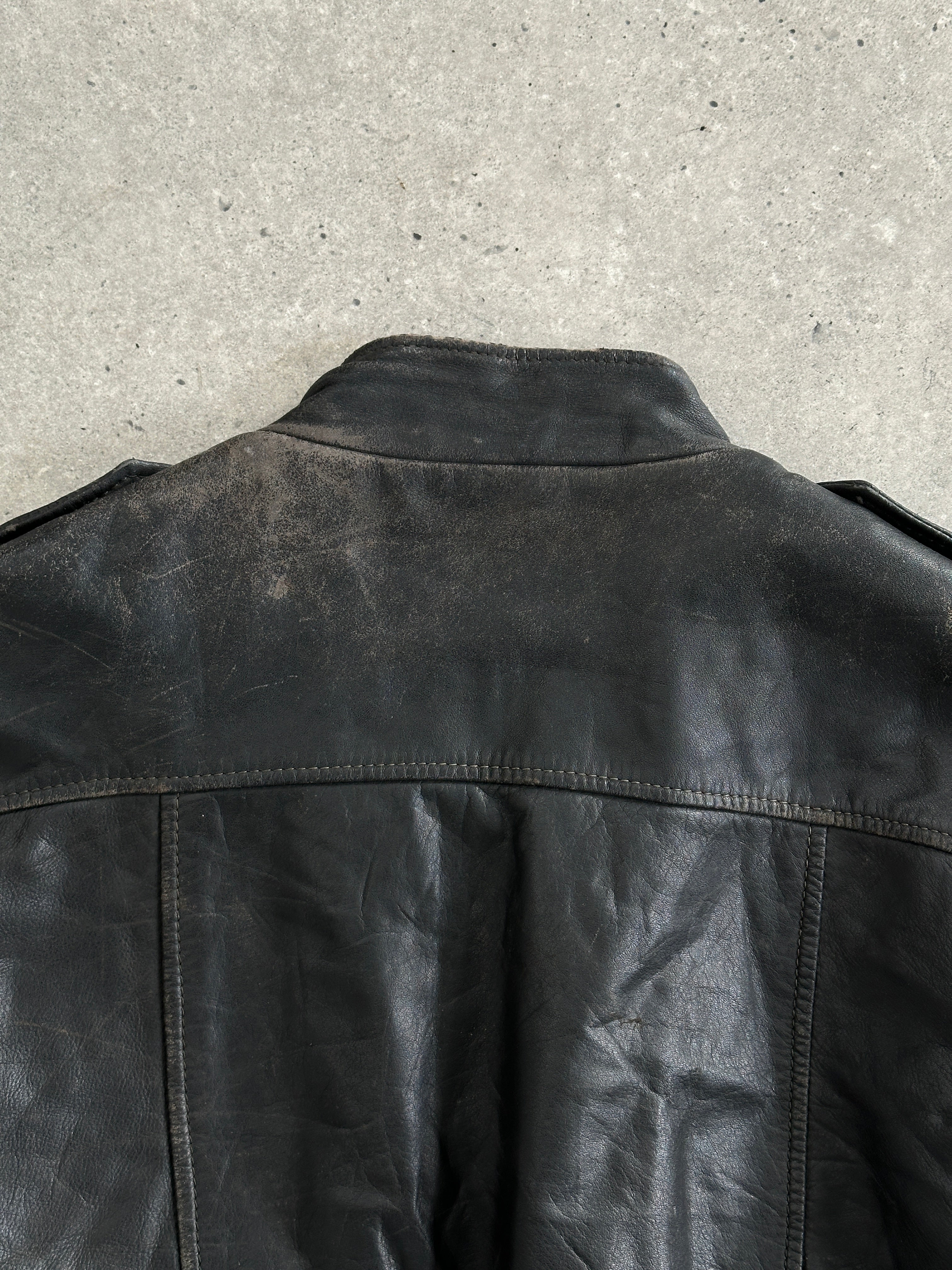Vintage distressed leather bomber jacket, size M/L, with rugged details and classic design, displayed on a hanger.