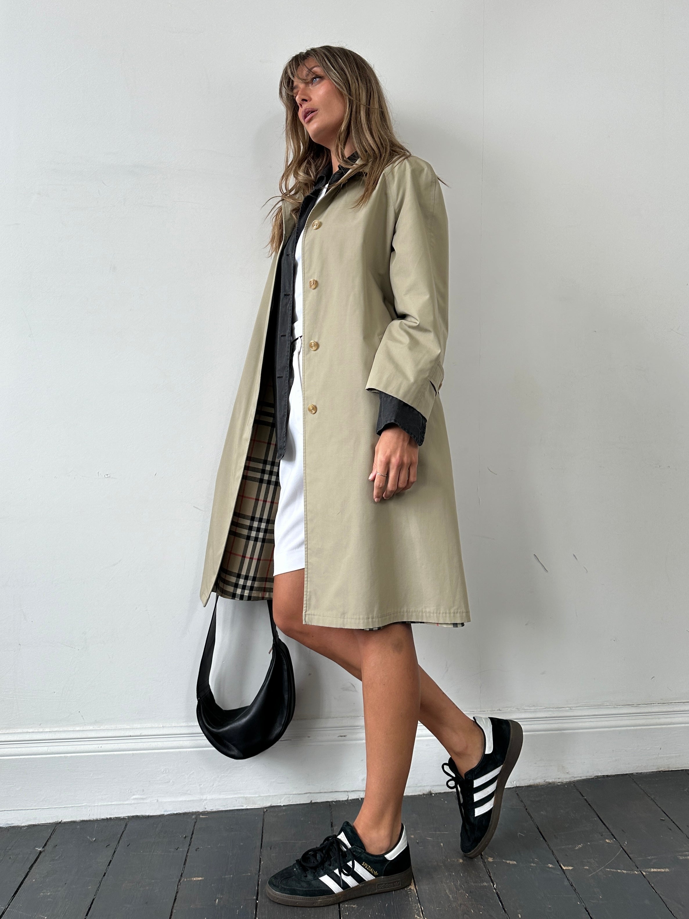 Vintage showerproof belted trench coat in size M, featuring classic design and waterproof fabric, displayed on a hanger.