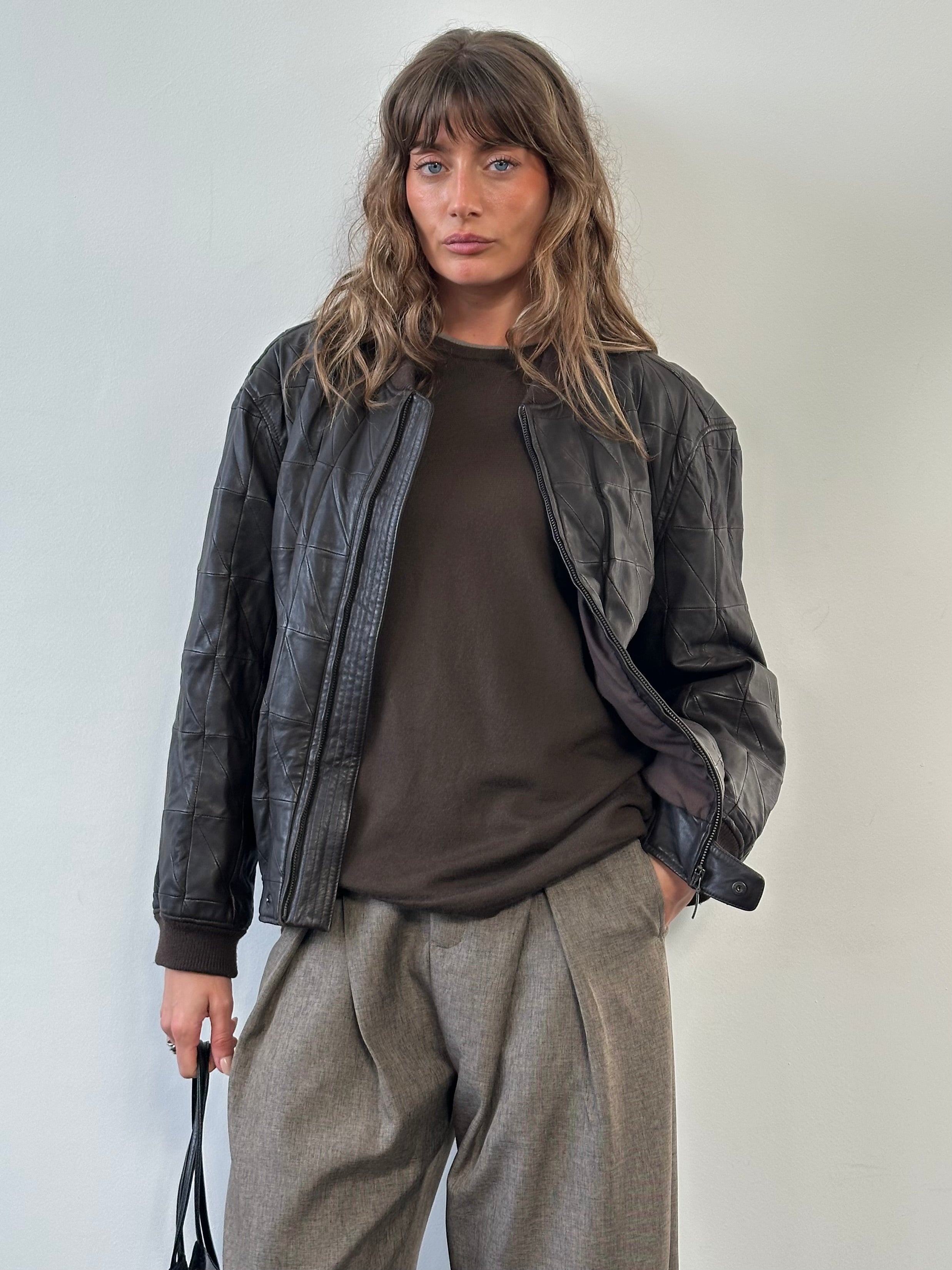 Armani Collezioni 2000s leather bomber jacket in black, featuring classic design and zip closure, displayed on a hanger.