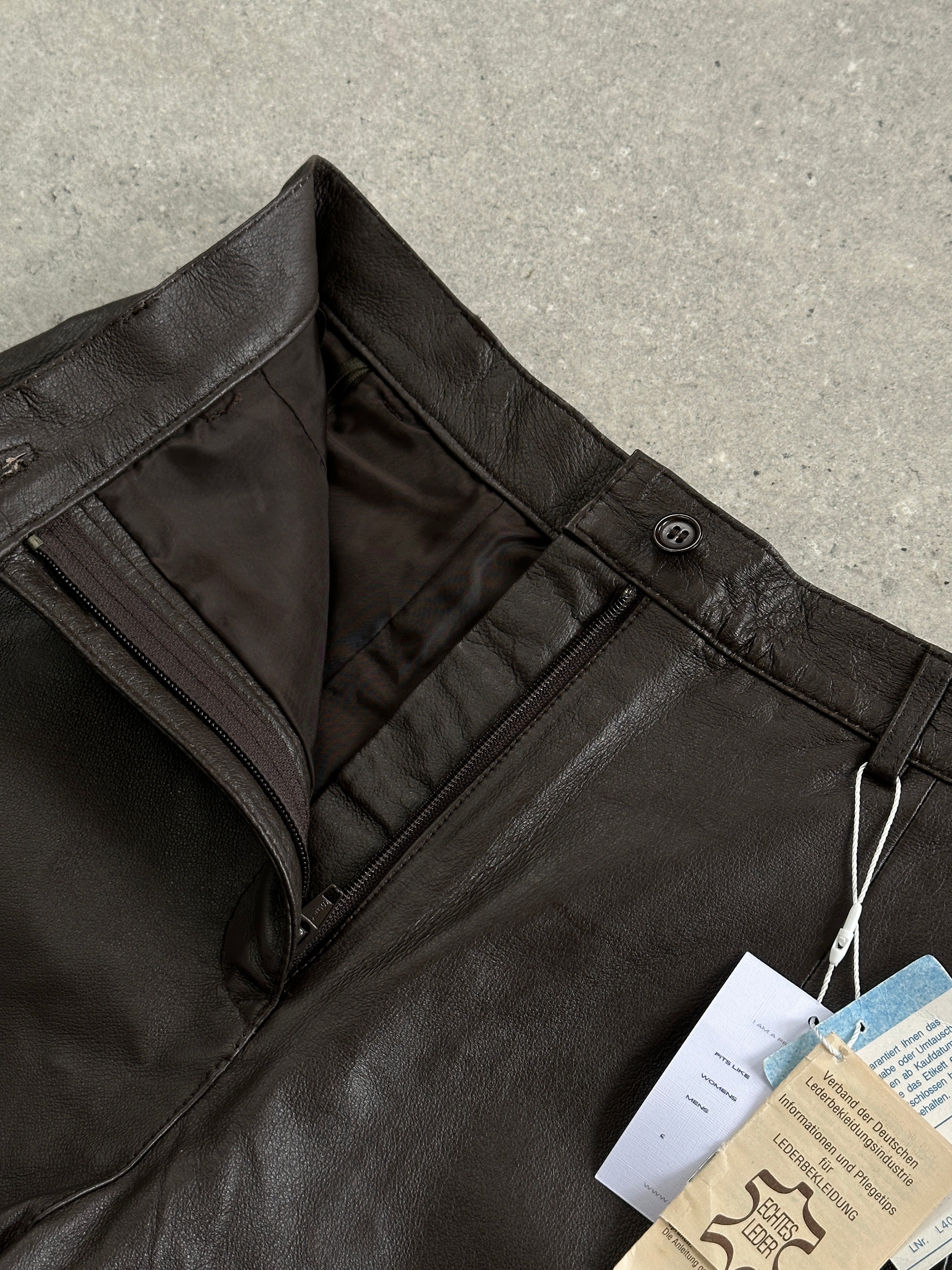 Vintage 2000s leather high-waisted mini shorts in size W26, showing a close-up of black leather fabric and high waist design.