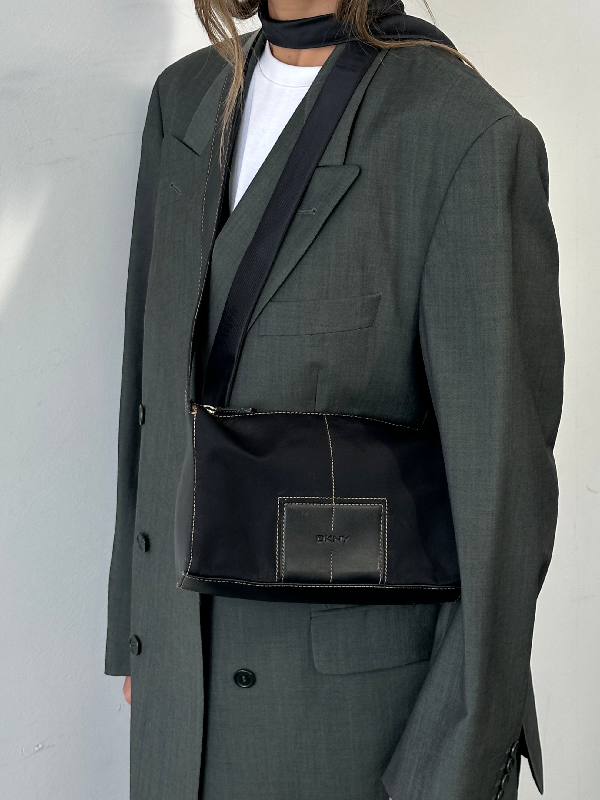 DKNY contrast stitch crossbody bag with sleek design and adjustable strap, featuring multiple compartments and stylish details.