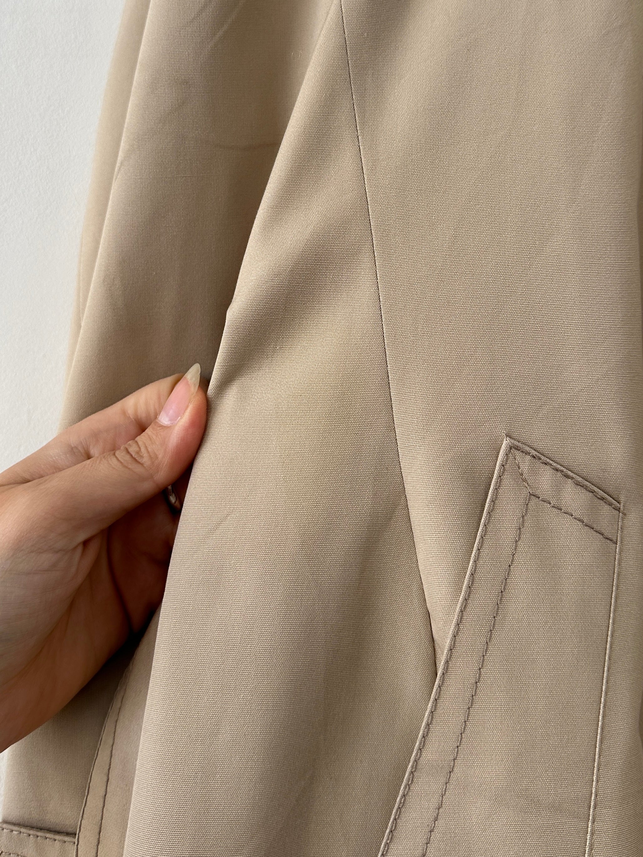 Vintage double-breasted belted trench coat in classic style, shown on a hanger with detailed fabric and belt features.
