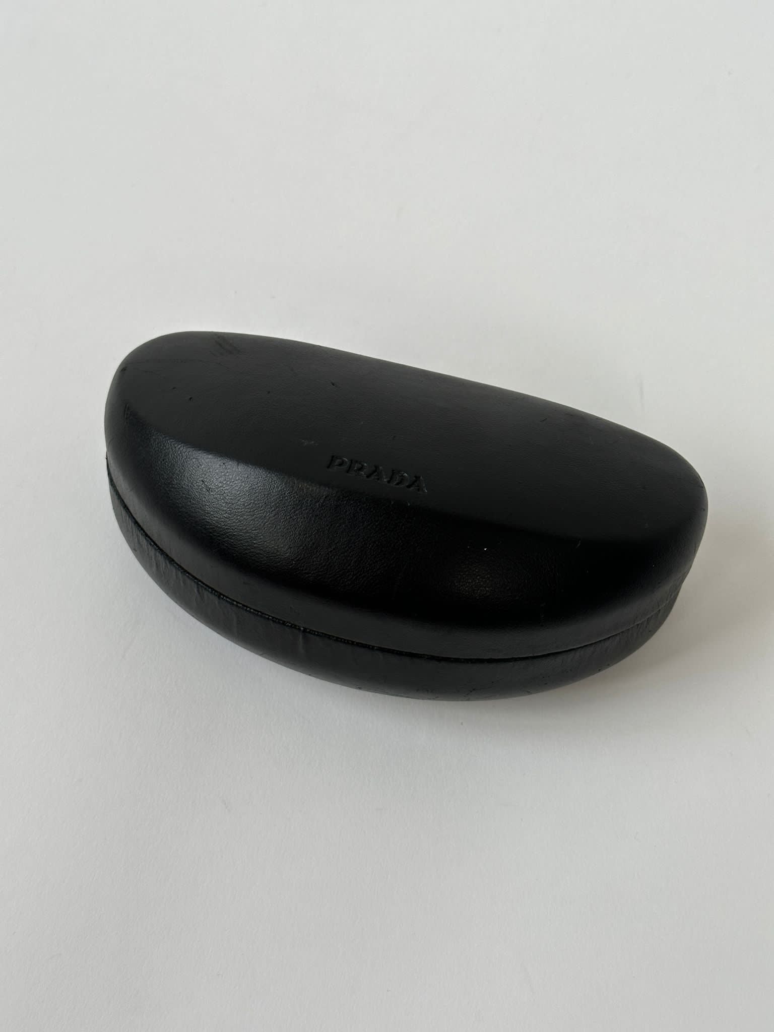 Prada Flame Rimless Wrap Sunglasses with sleek black frames and tinted lenses, designed for modern style and sun protection.