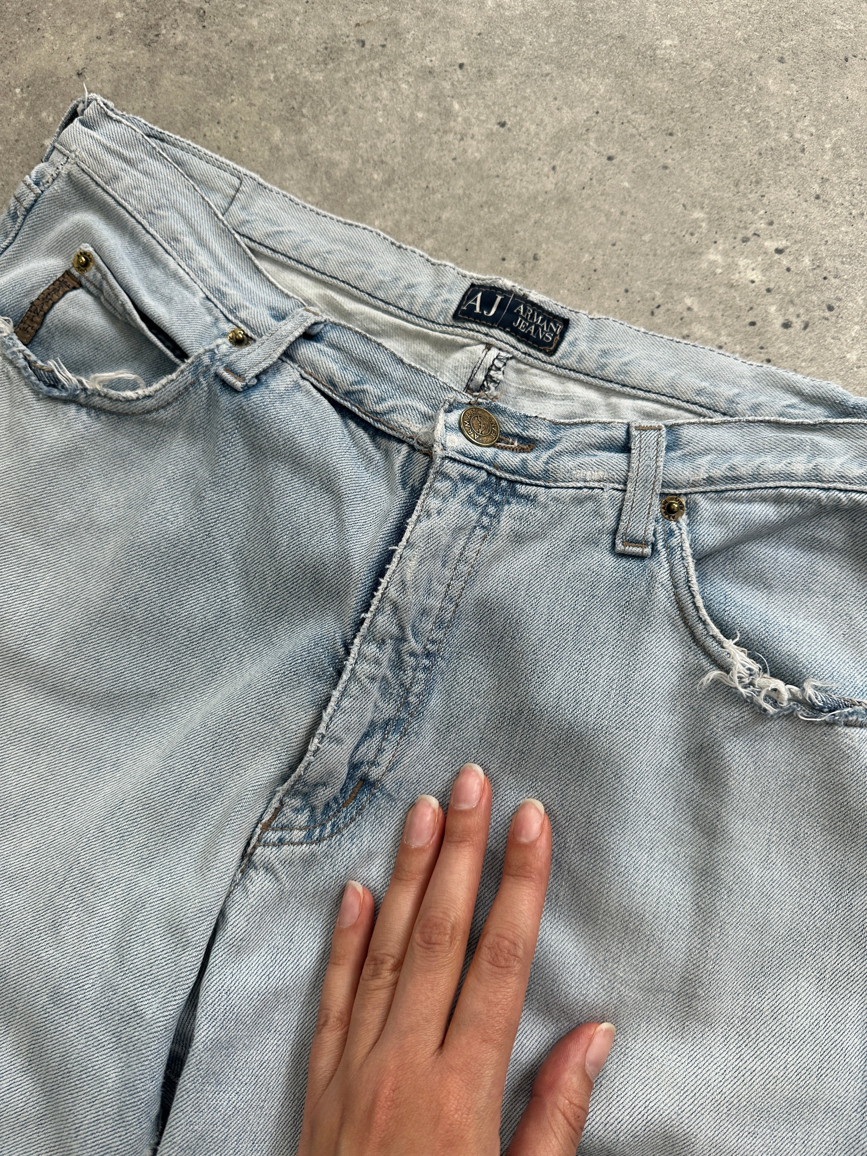 Light wash Armani Jeans mid-rise denim jeans with belt loops and pockets, displayed laid flat.