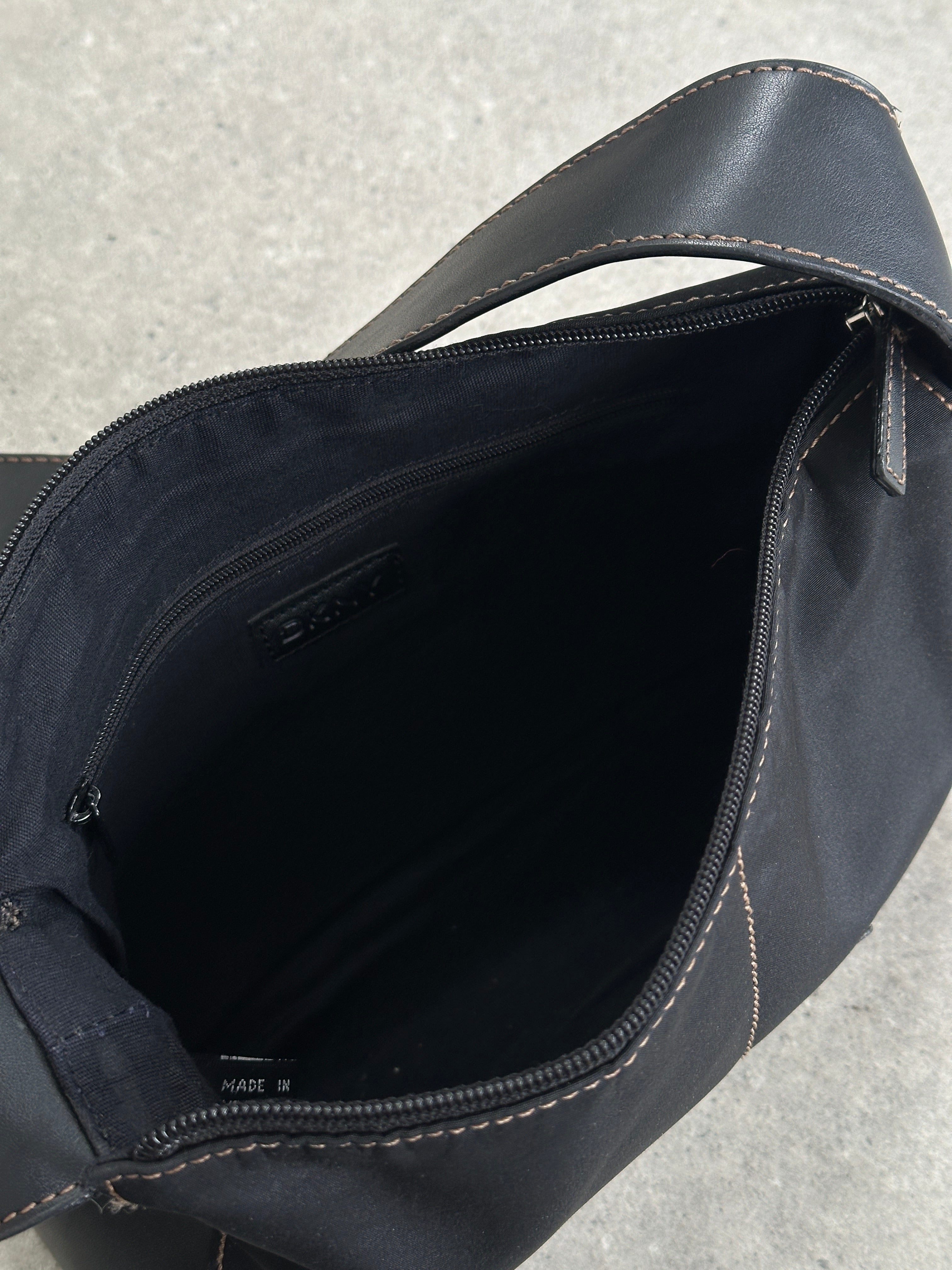 DKNY contrast stitch crossbody bag with adjustable strap and logo detail, showcasing stylish design and durable material.