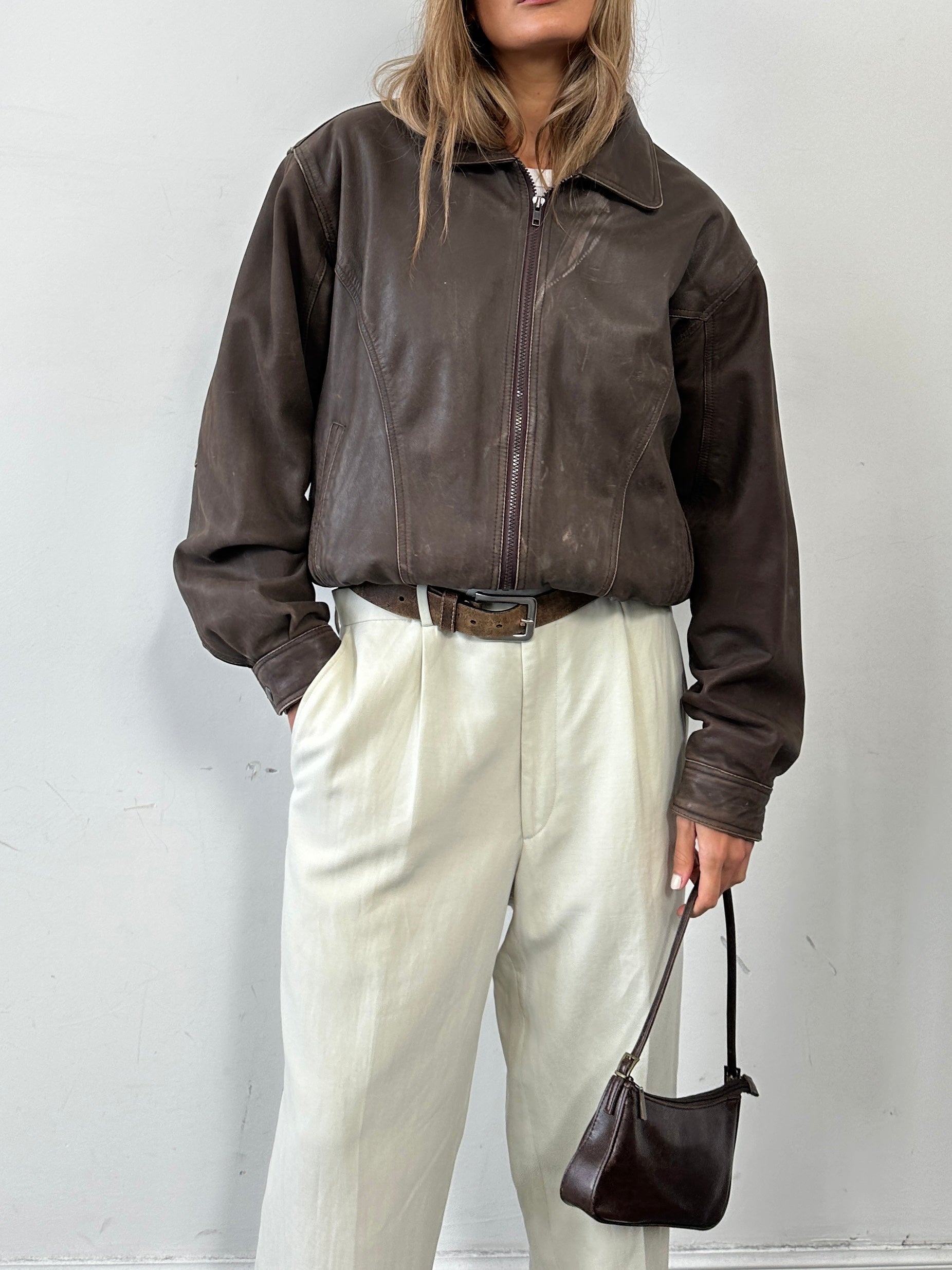Vintage distressed leather bomber jacket in size M, featuring classic design with worn, rugged texture and metal zipper details.