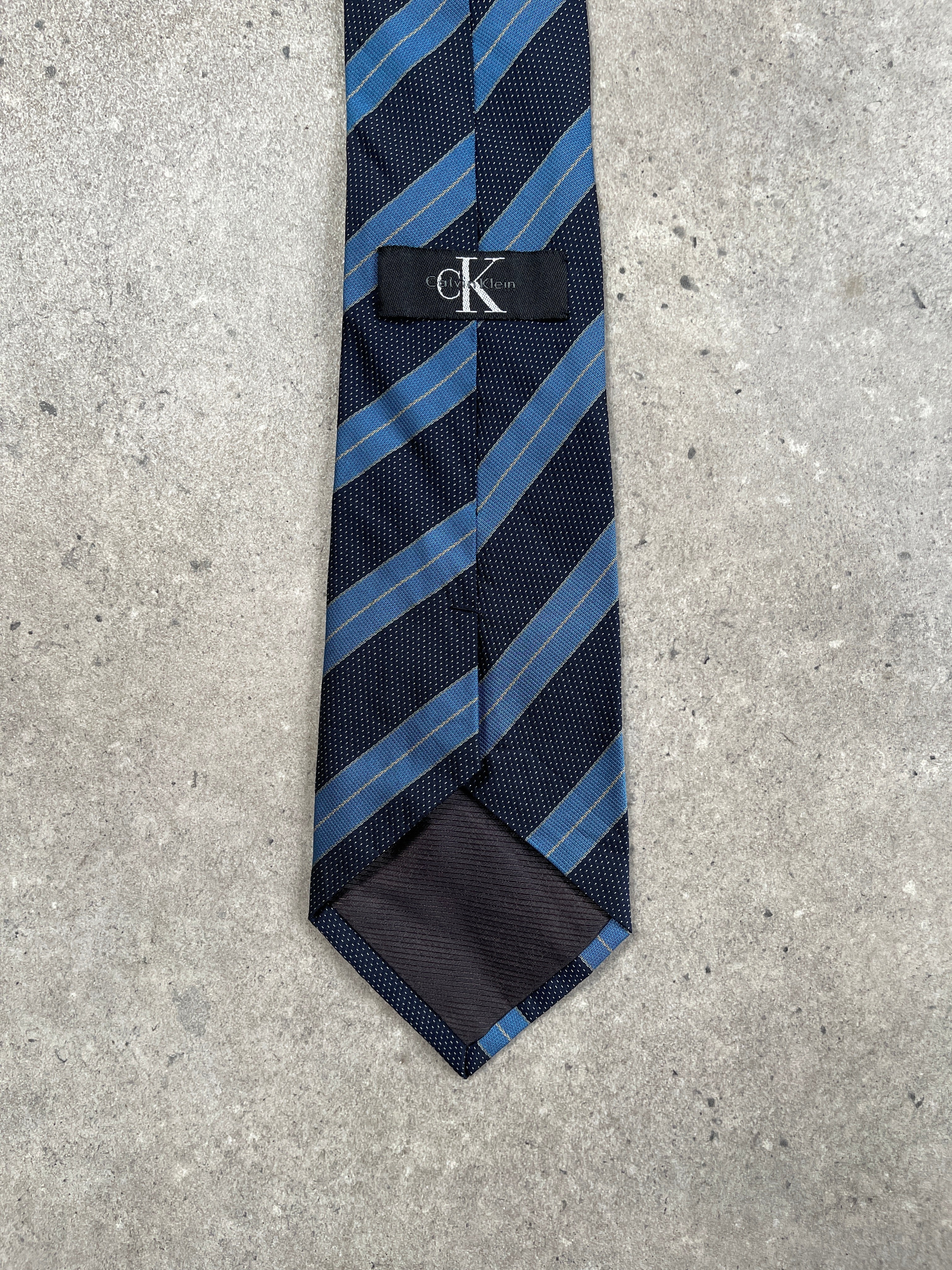 Calvin Klein CK 1990s diagonal stripe tie with navy and white pattern, showcasing classic design and fabric texture.