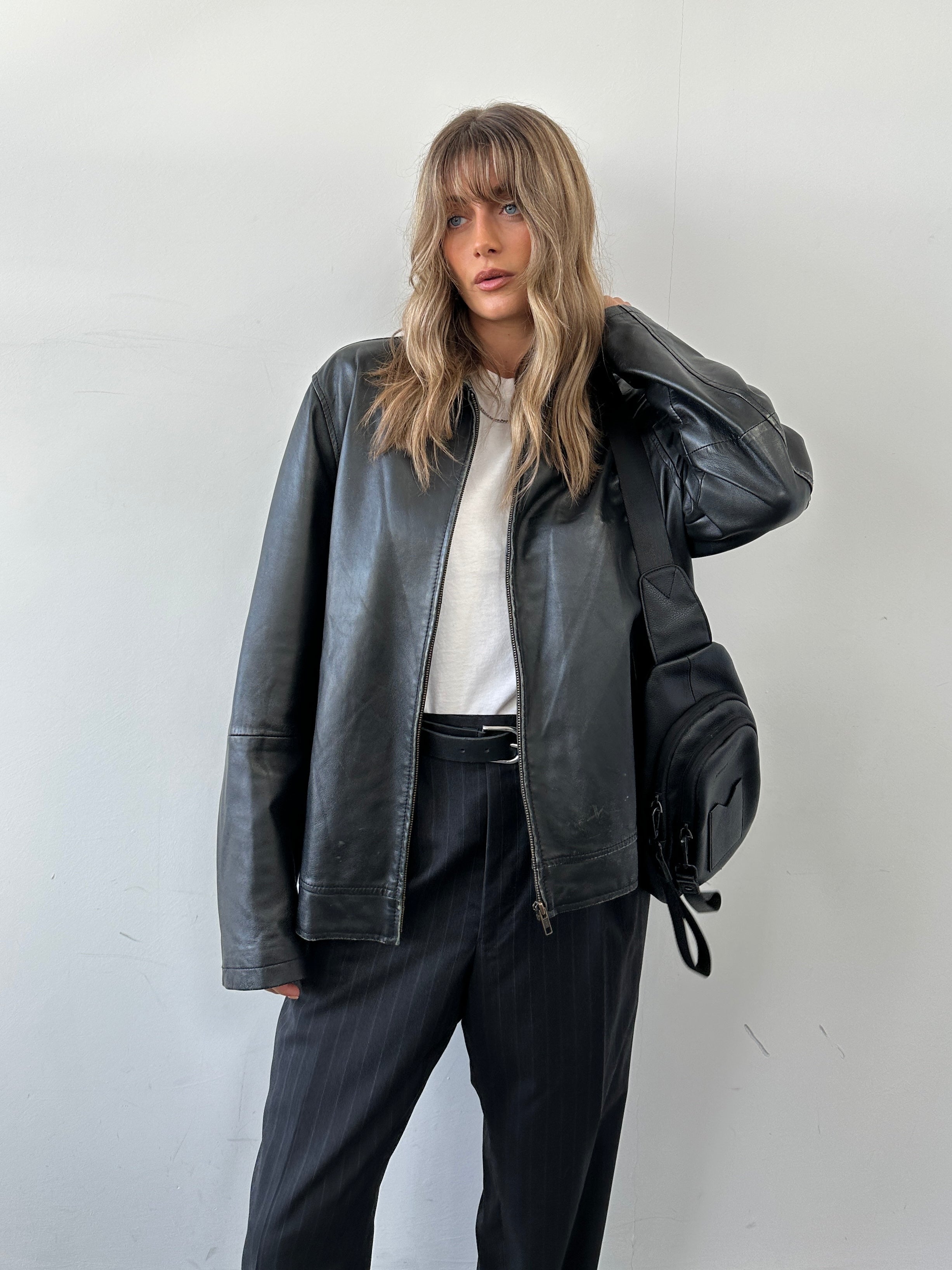 Conbipel minimal leather jacket in size L, black, with sleek design, shown on a hanger highlighting its smooth leather texture.