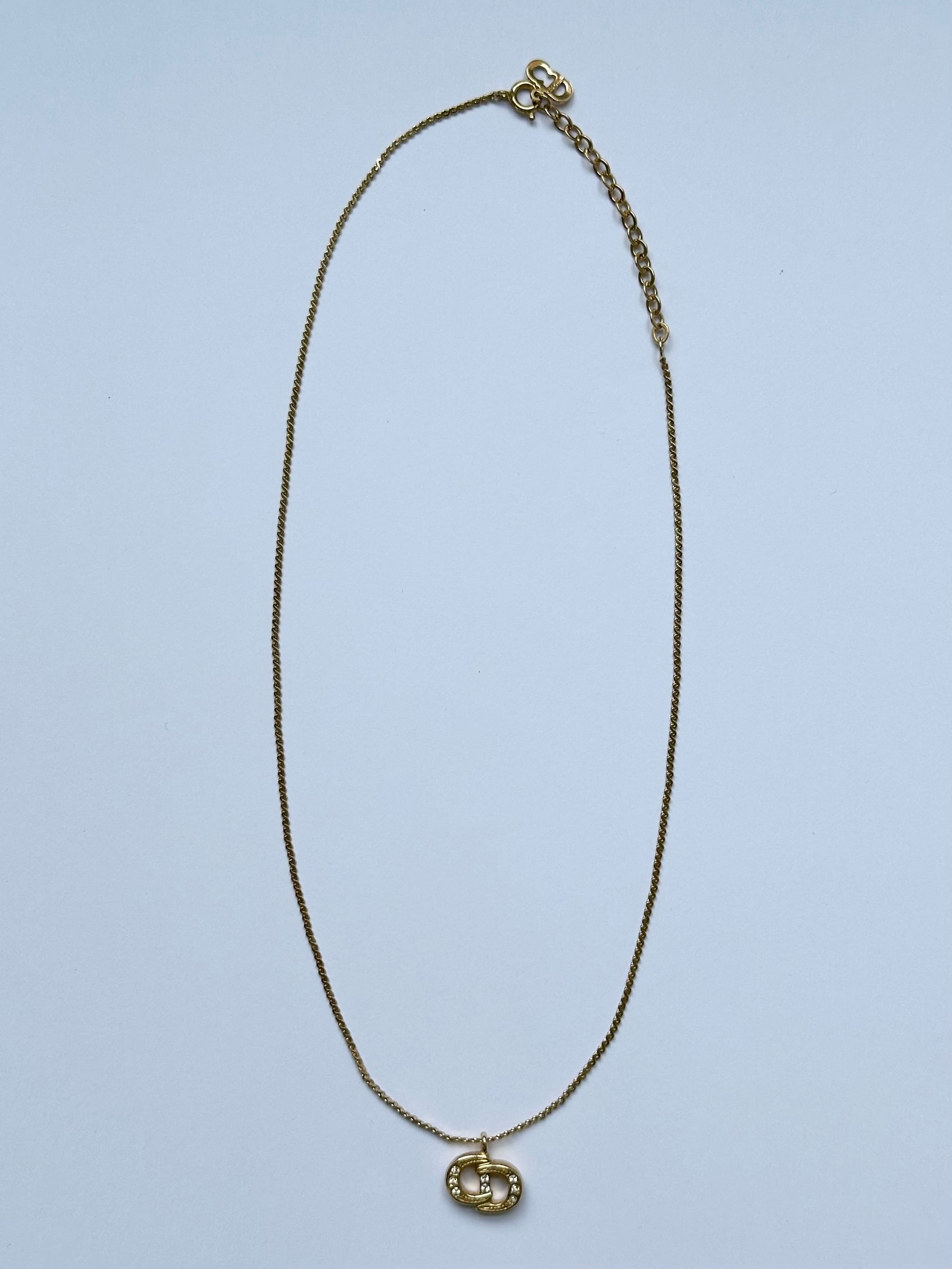 Christian Dior 16-inch gold plated rhinestone logo pendant necklace hanging with detailed rhinestone embellishments.