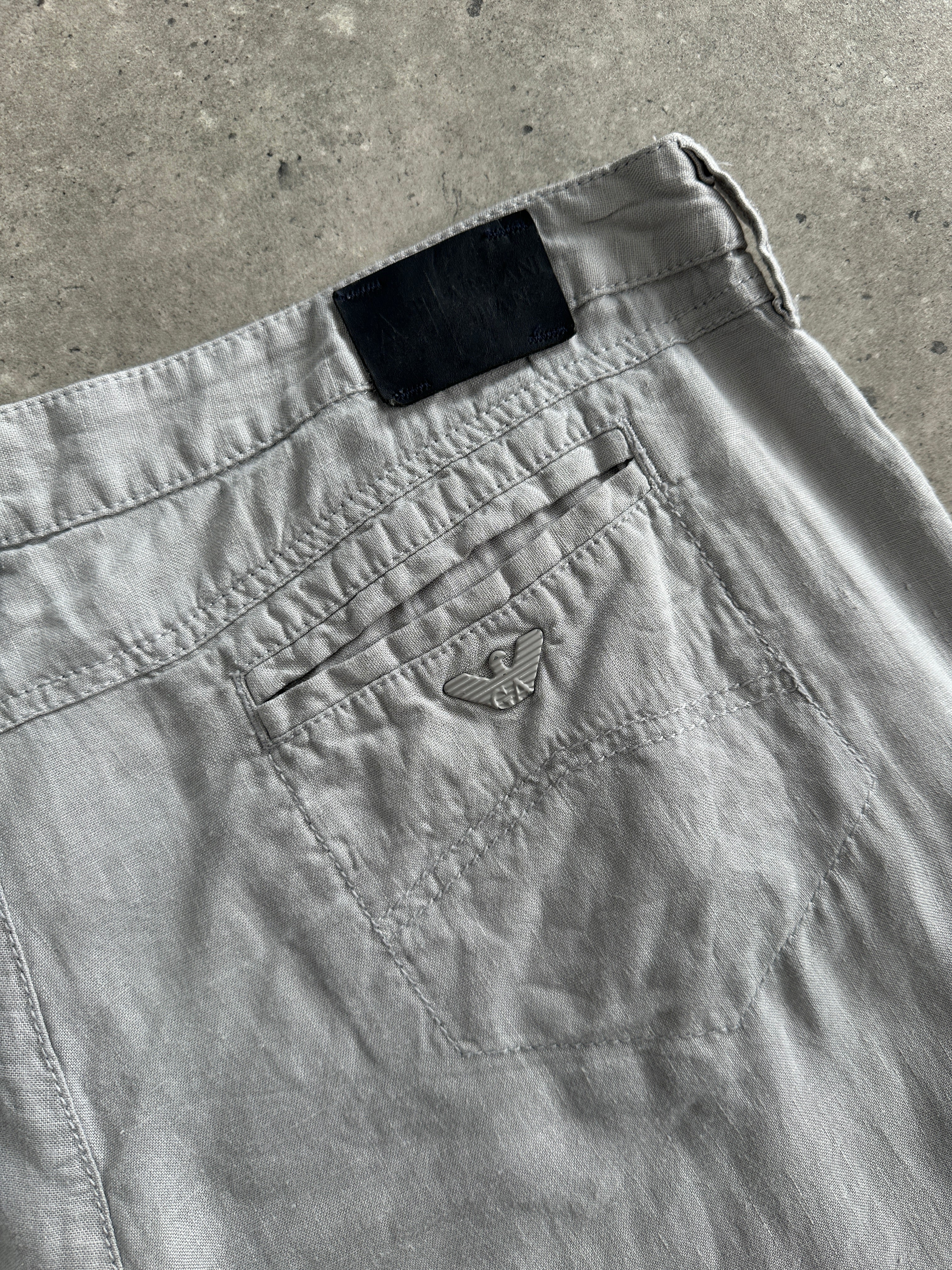 Armani Jeans pure linen flared trousers in size W33 displayed on a hanger, showing their lightweight fabric and relaxed fit.
