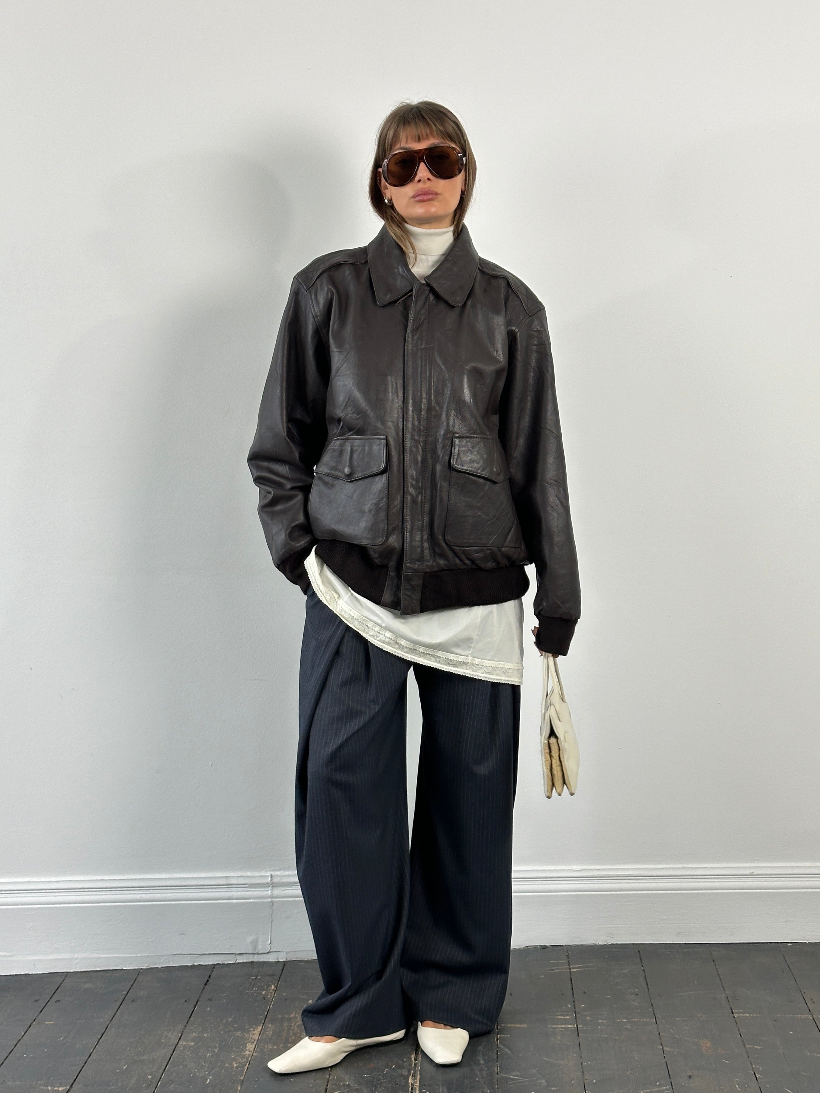 Vintage 1990s leather bomber jacket with concealed placket, XL size, featuring classic design and distressed leather texture.