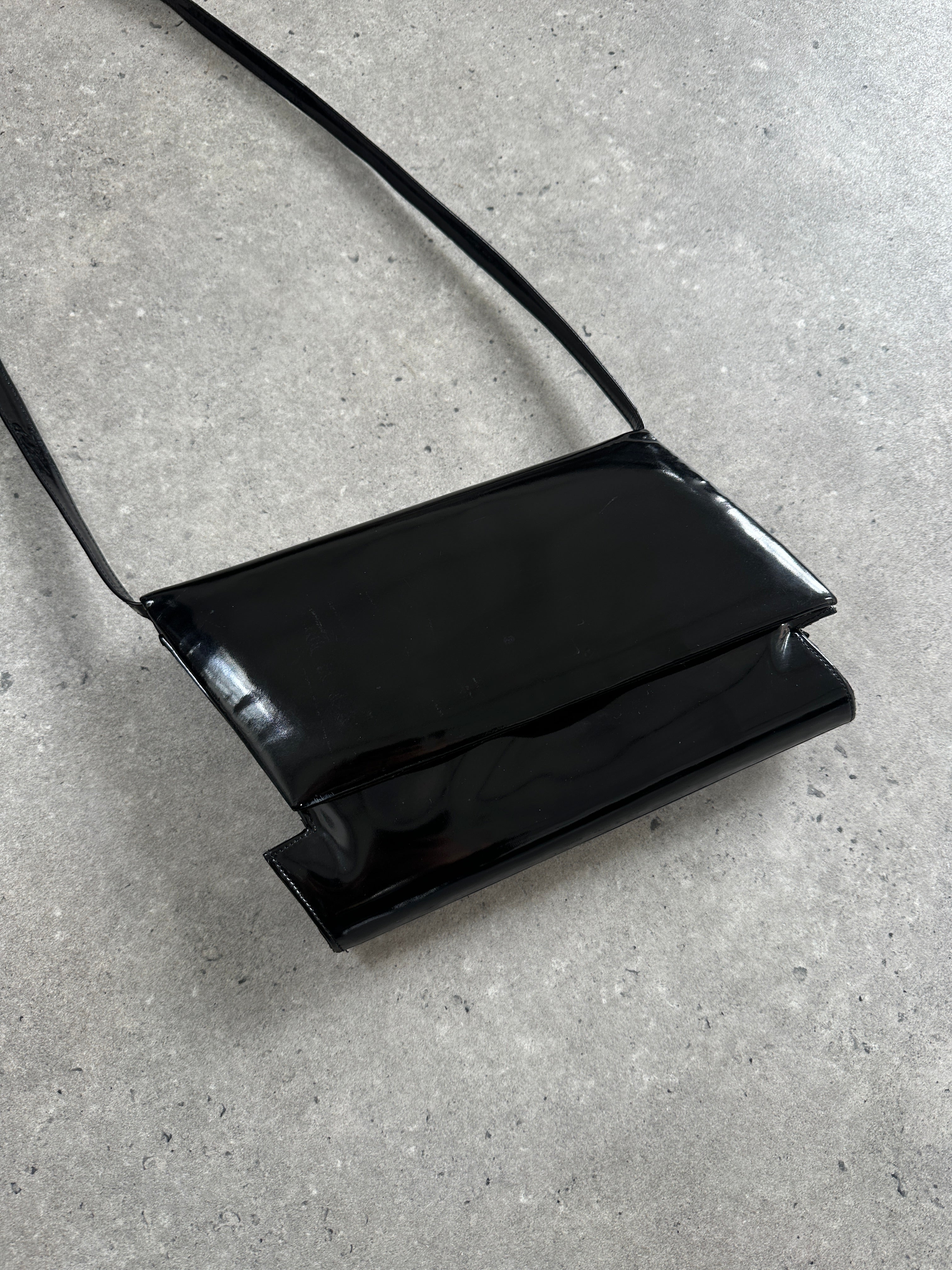 Charles Jourdan 1990s asymmetric patent crossbody bag featuring sleek design and unique shape, with a shoulder strap and glossy finish.