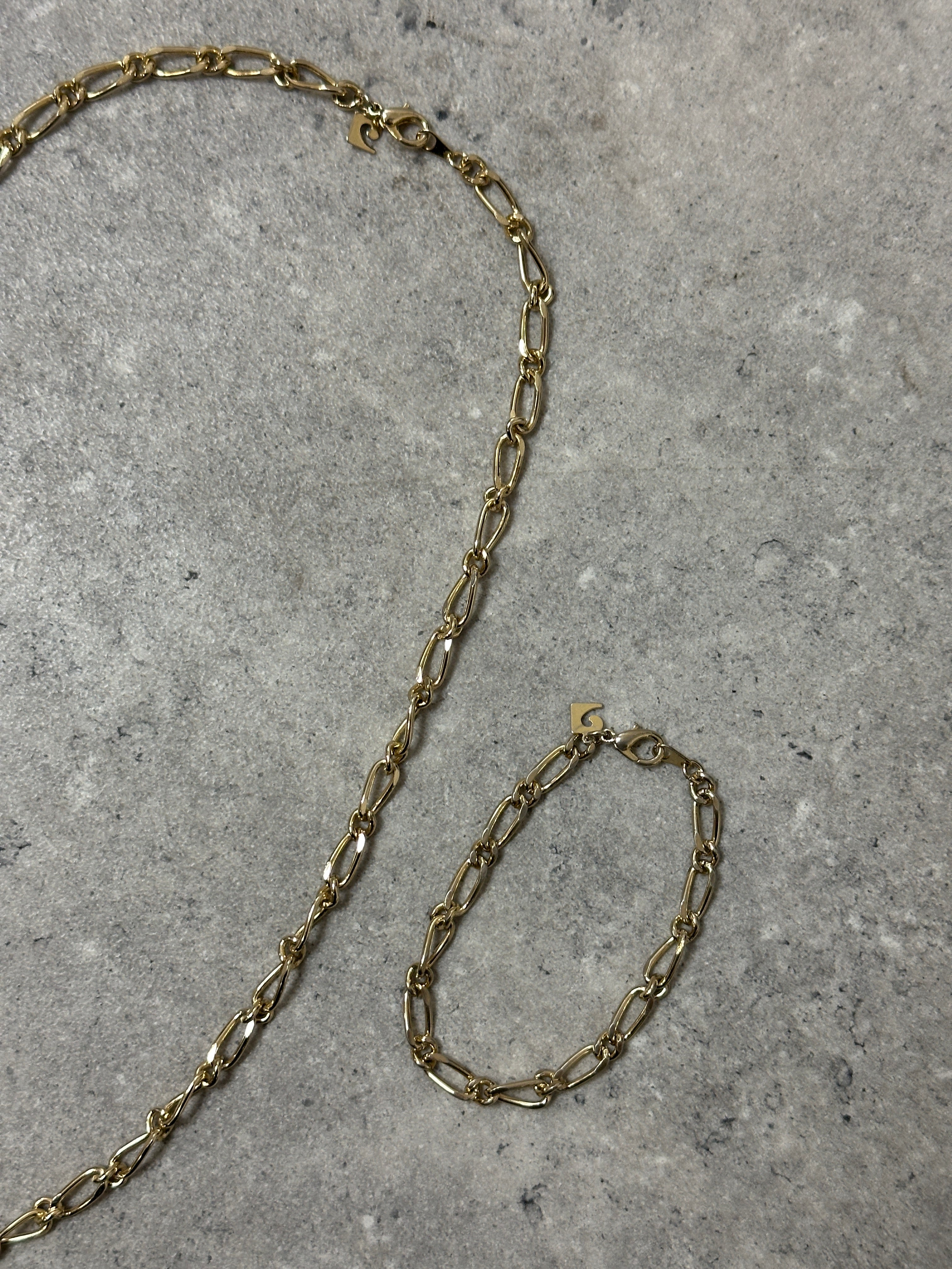 Pierre Cardin gold-plated necklace and bracelet chain set with sleek, shiny links displayed on a neutral background.