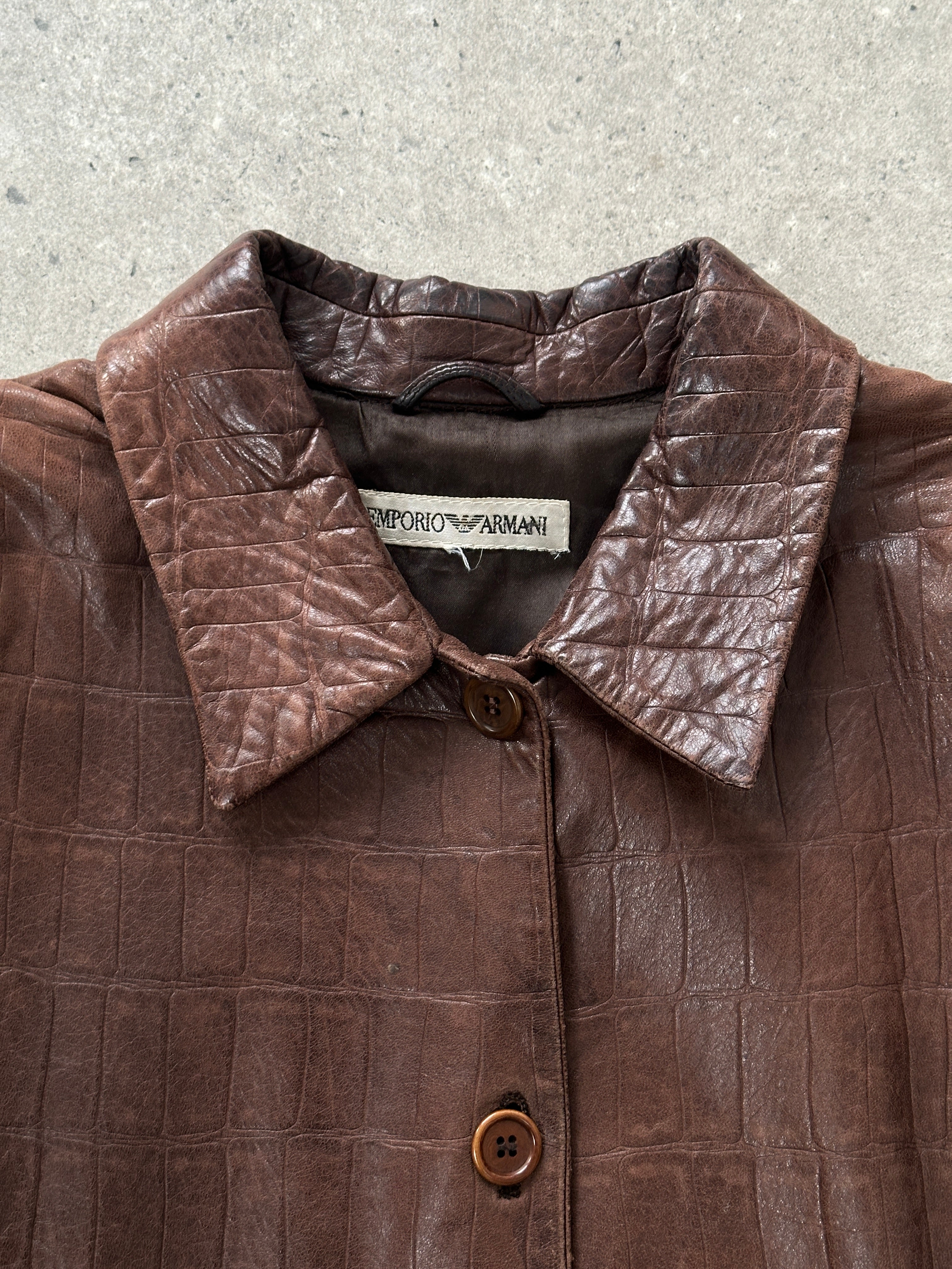 Emporio Armani 1990s black leather jacket with classic design, displayed on a hanger showcasing its sleek silhouette and high-quality material.