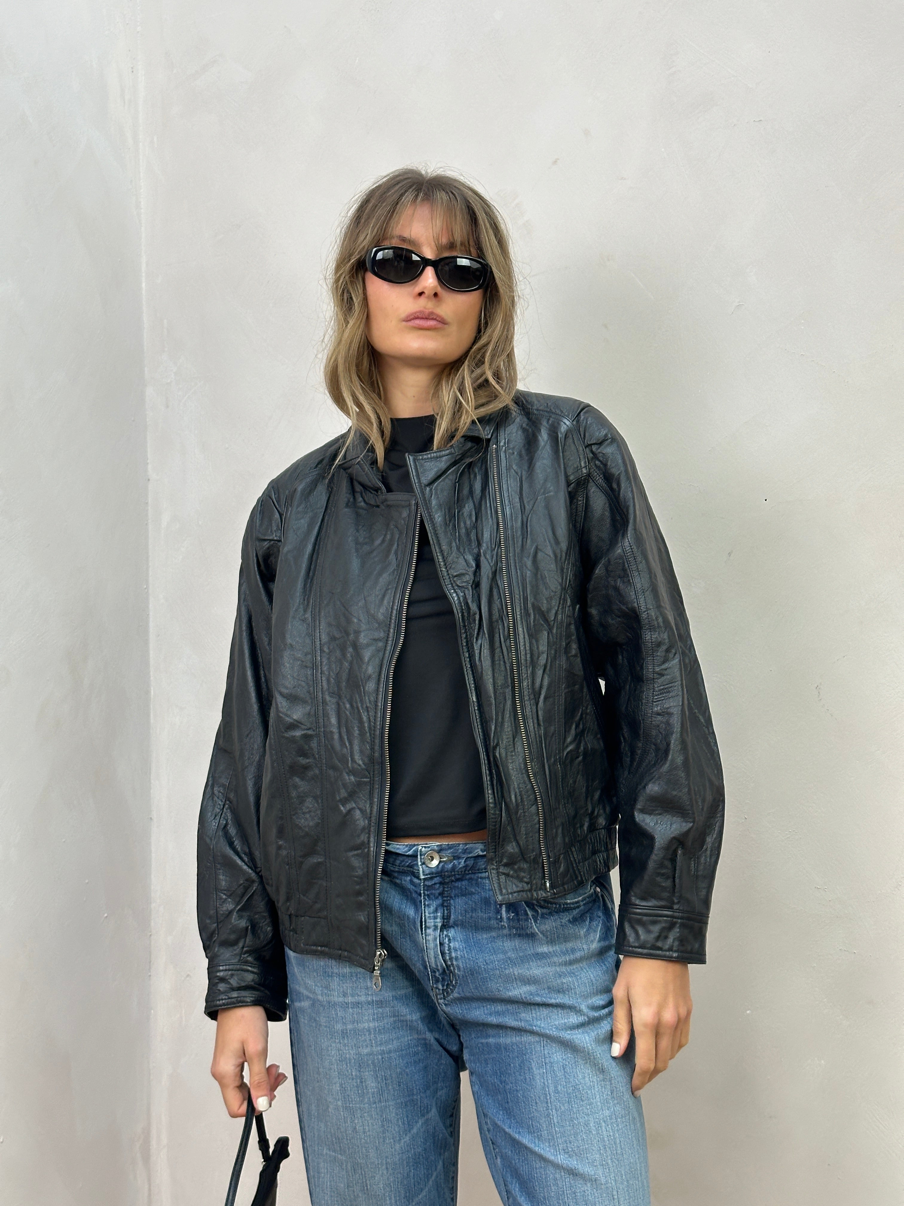 Vintage leather biker jacket in size S/M, featuring classic styling and aged leather, displayed on a hanger.
