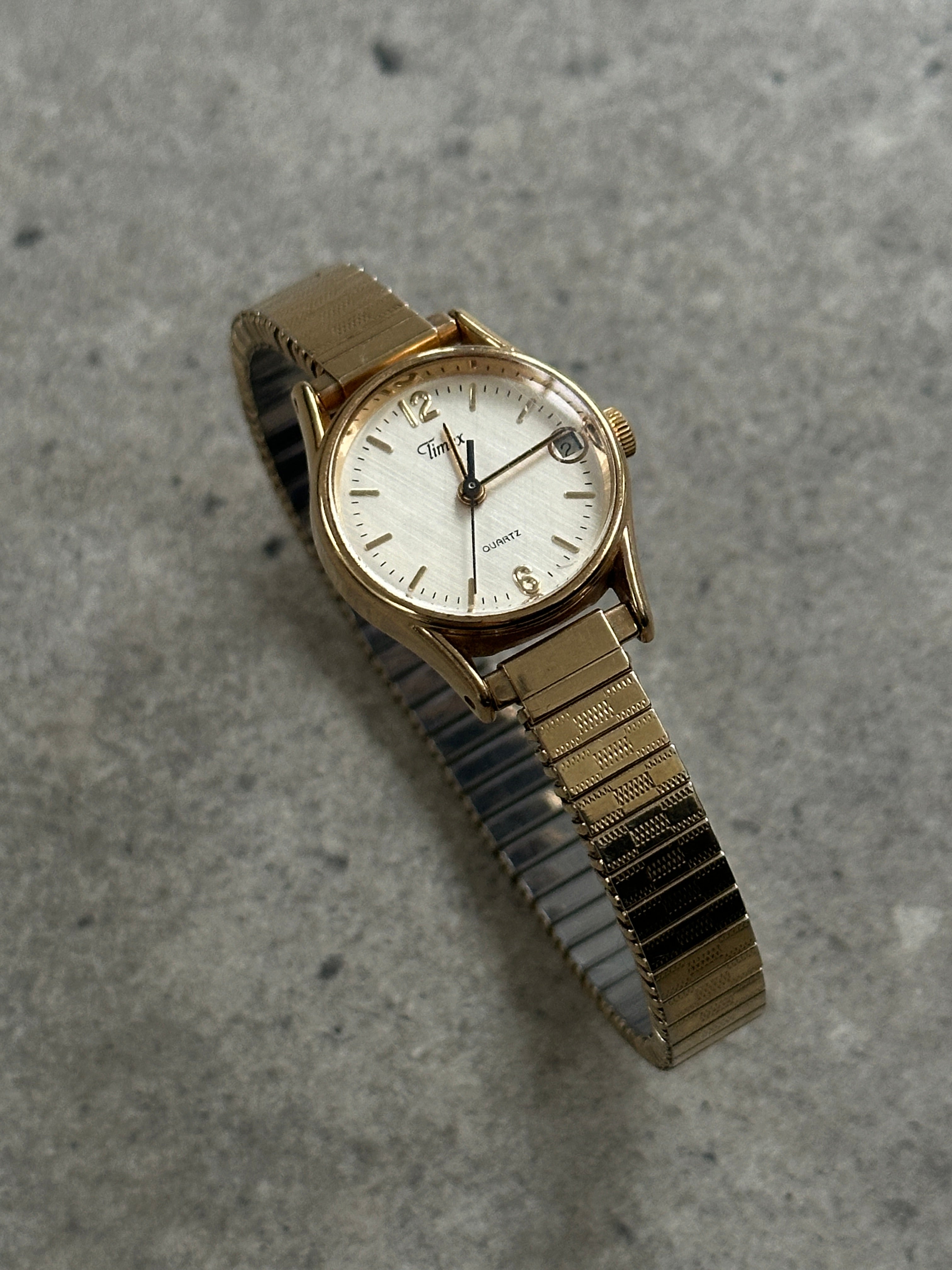 Timex 1990s round gold tone quartz watch with a classic design and metal bracelet.