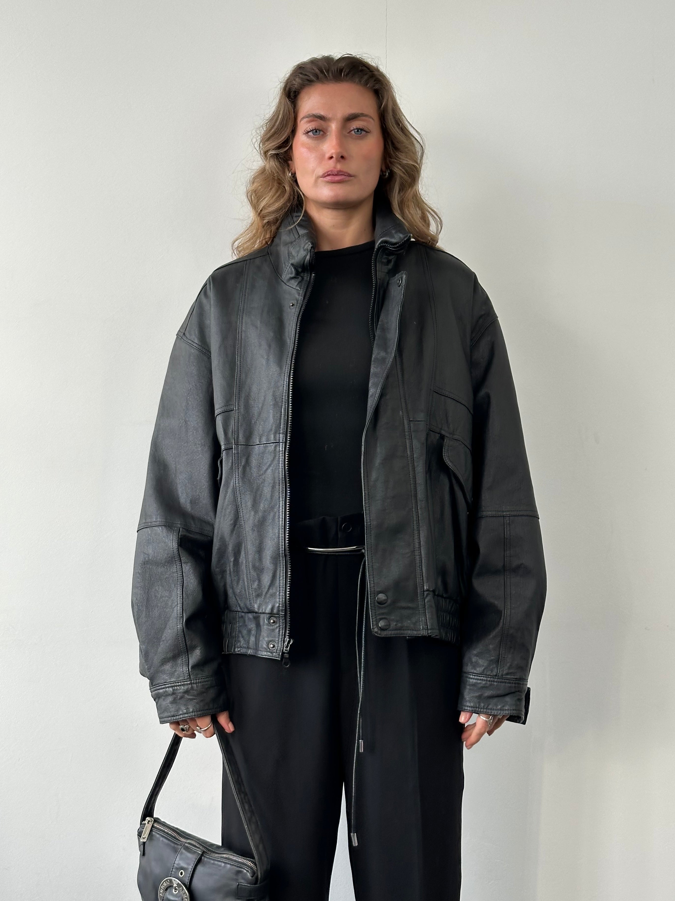 Vintage leather bomber jacket in size L, featuring classic design and detailed stitching, styled on a hanger.