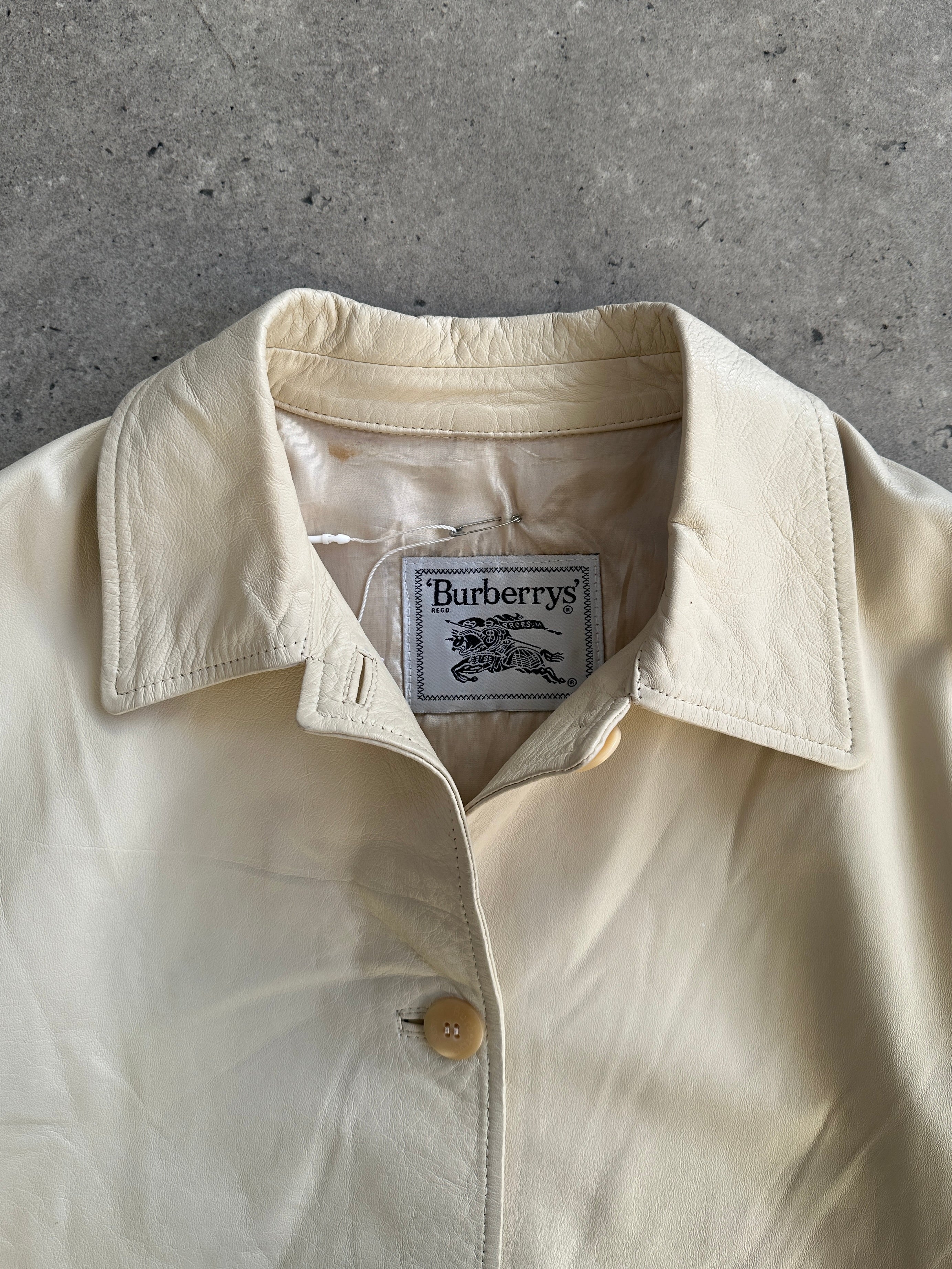 Burberry boxy leather jacket in black with visible stitching and classic collar, displayed on a hanger.