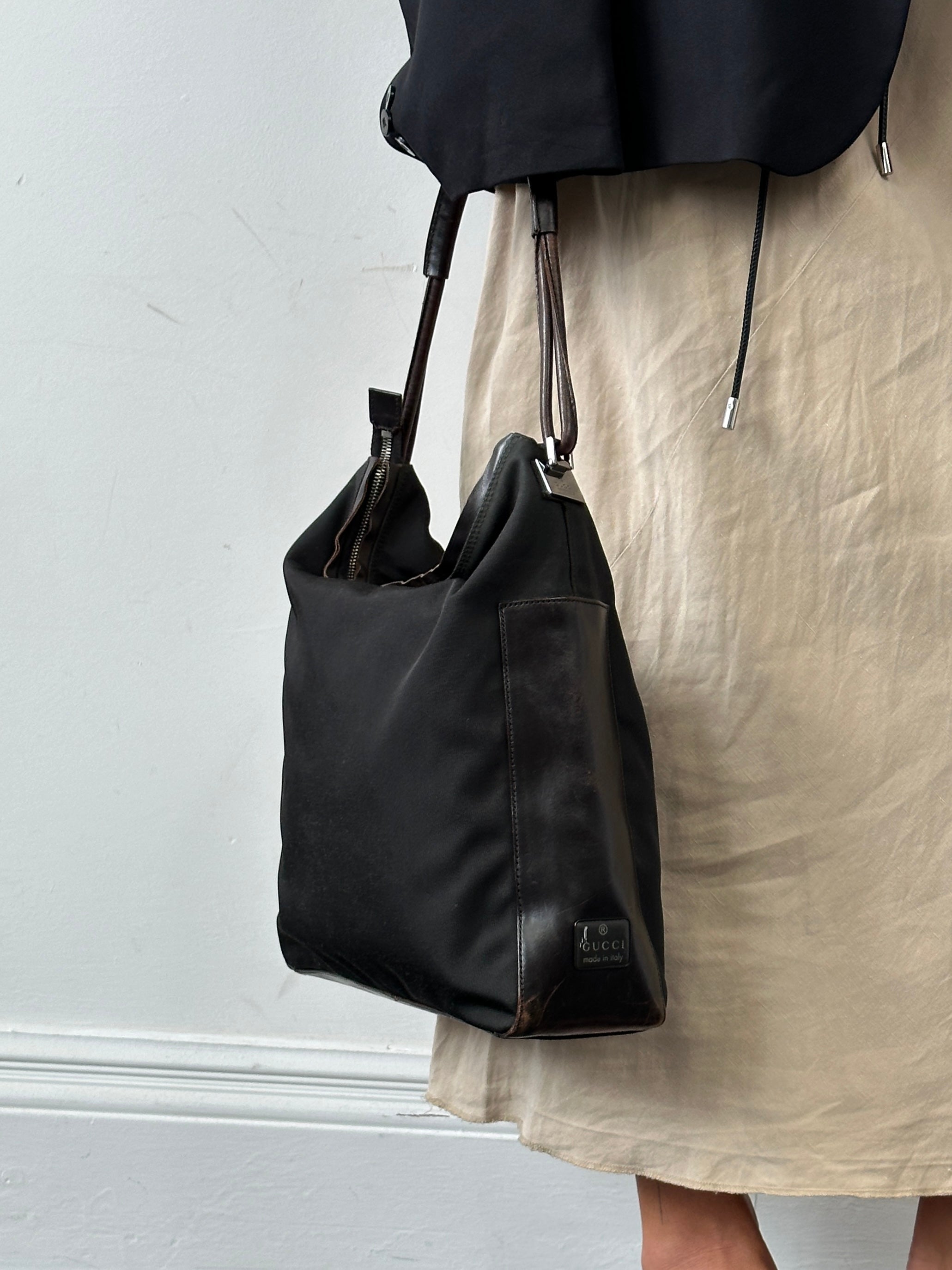 Gucci canvas leather shoulder bag with adjustable strap, featuring the iconic GG pattern and sleek design.